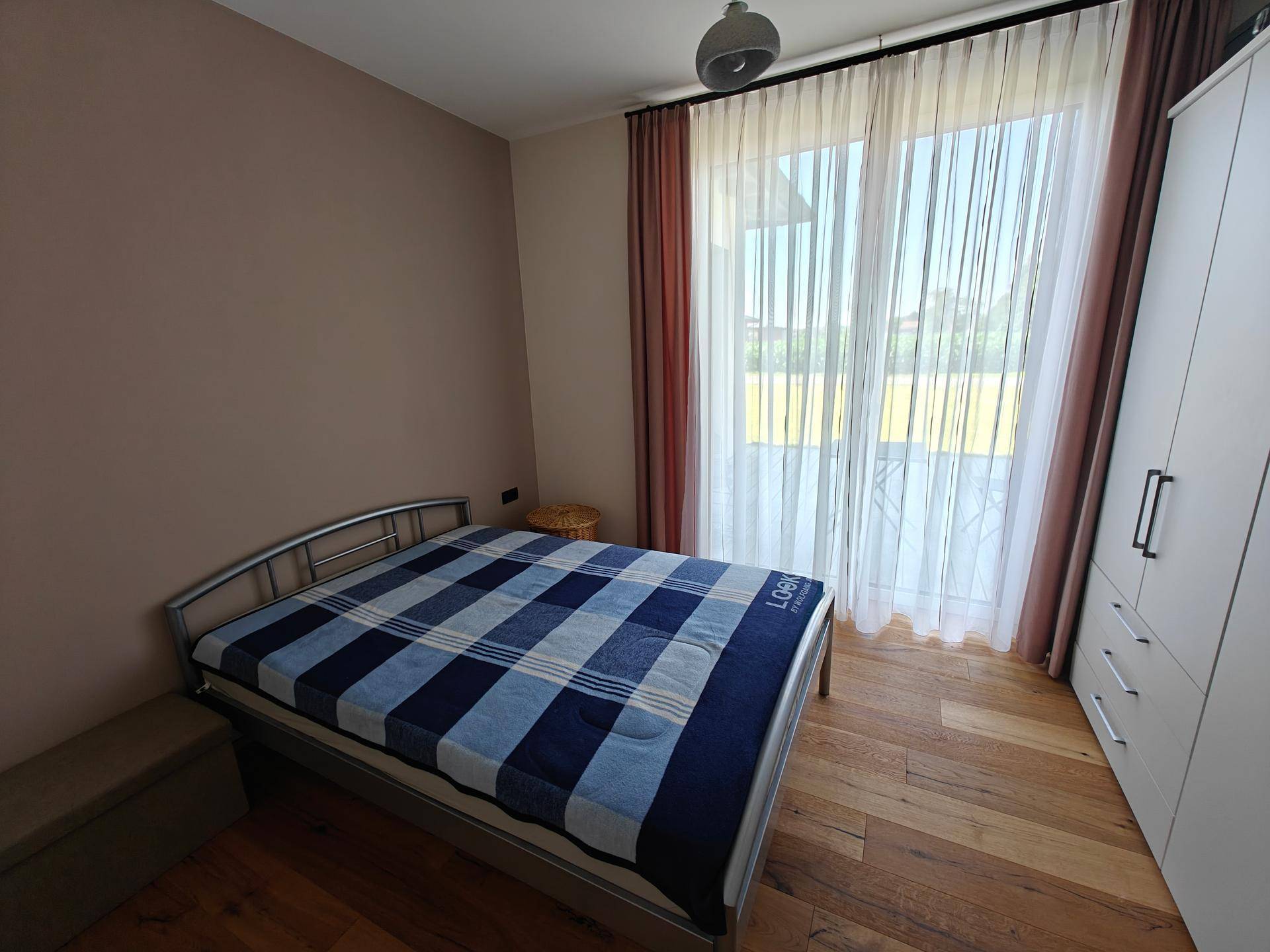 Helles Schlafzimmer mit Einzelbett und Zugang zu einem Außenbereich durch eine große Fenstertür.