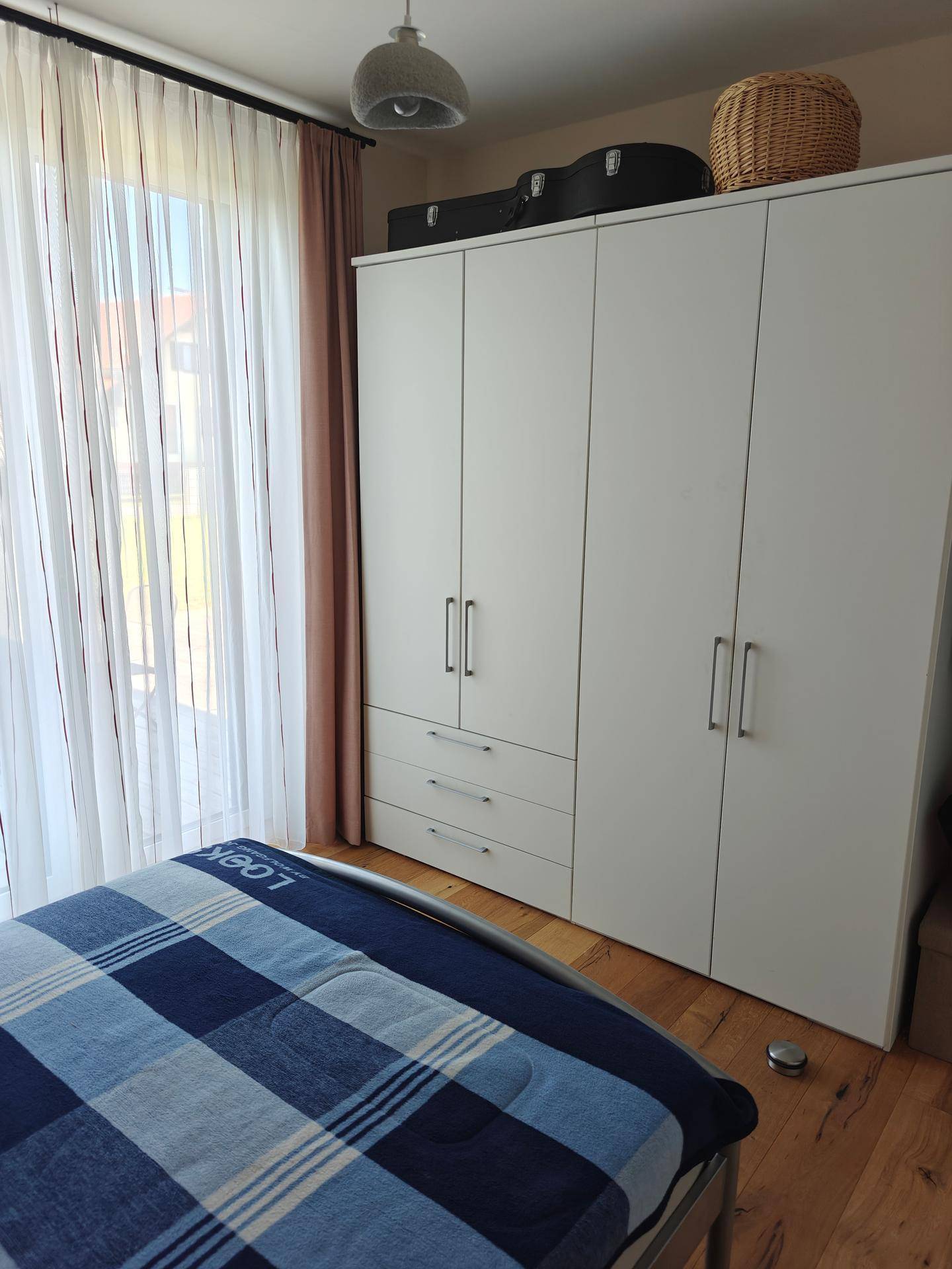 Schlafzimmer mit Einzelbett und einem geräumigen weißen Kleiderschrank.