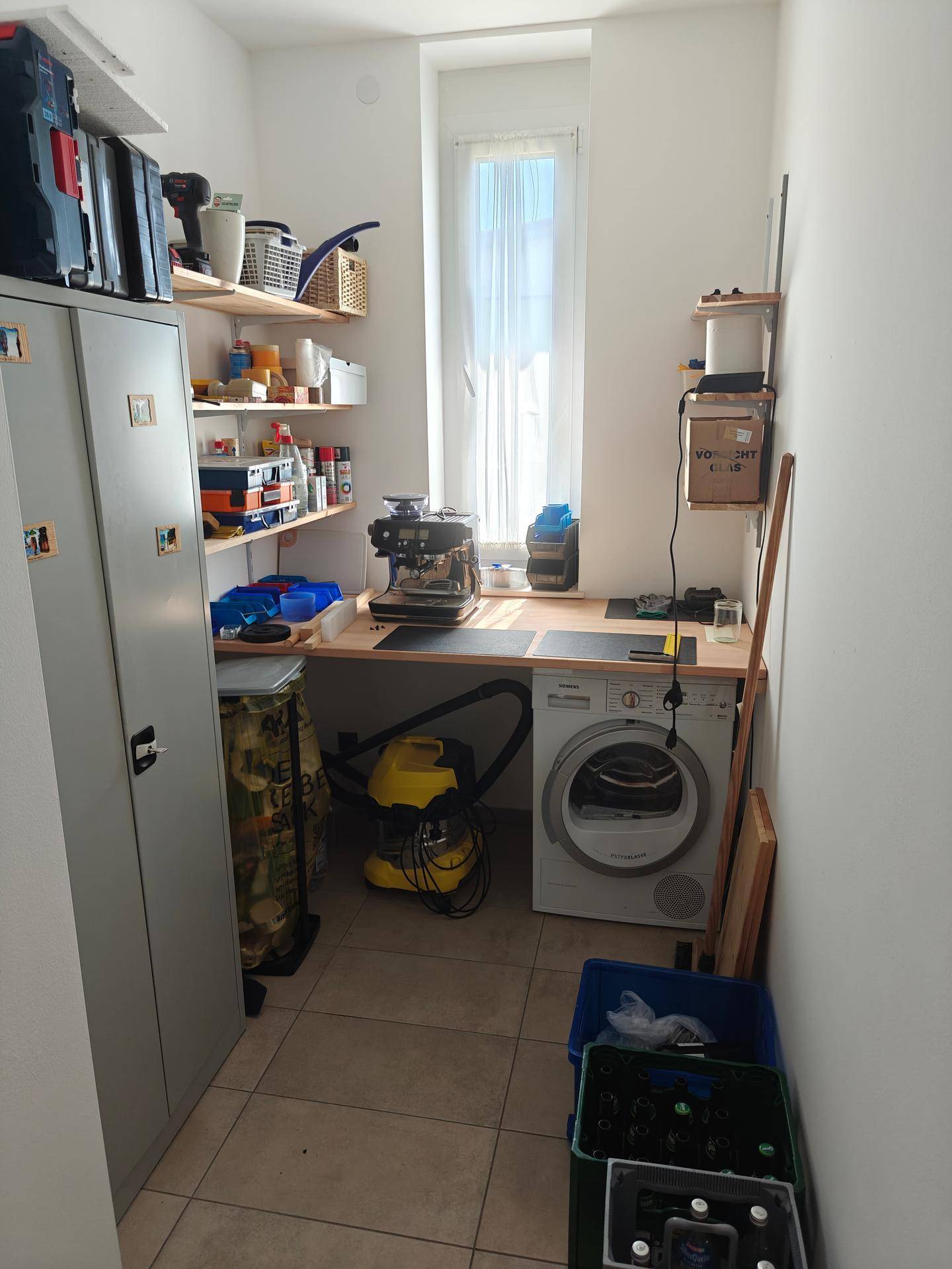 Praktischer Hauswirtschaftsraum mit Waschmaschine, Arbeitsfläche und viel Stauraum.