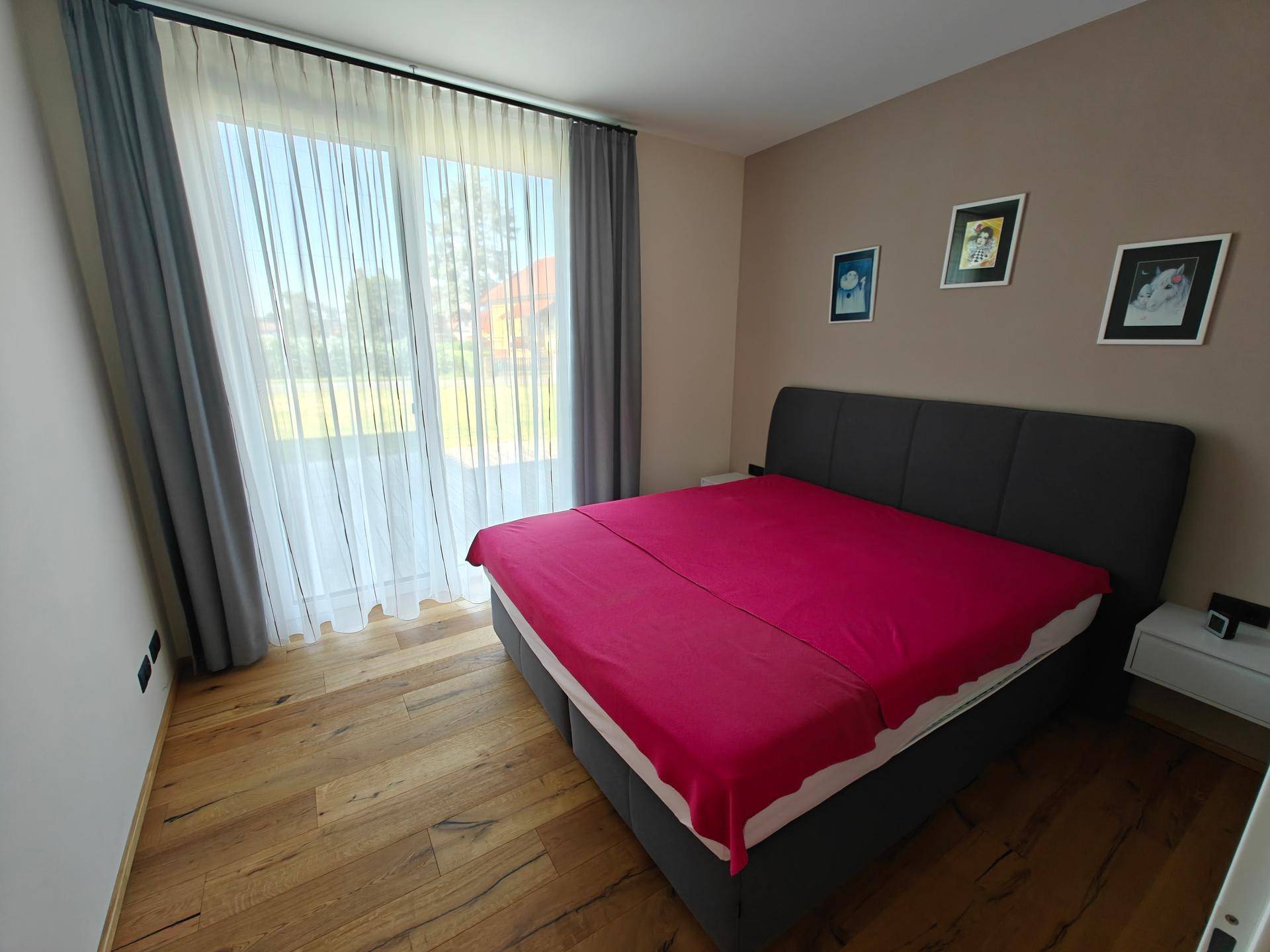 Schlafzimmer mit großem Doppelbett und bodentiefen Fenstern, die viel Licht hereinlassen.