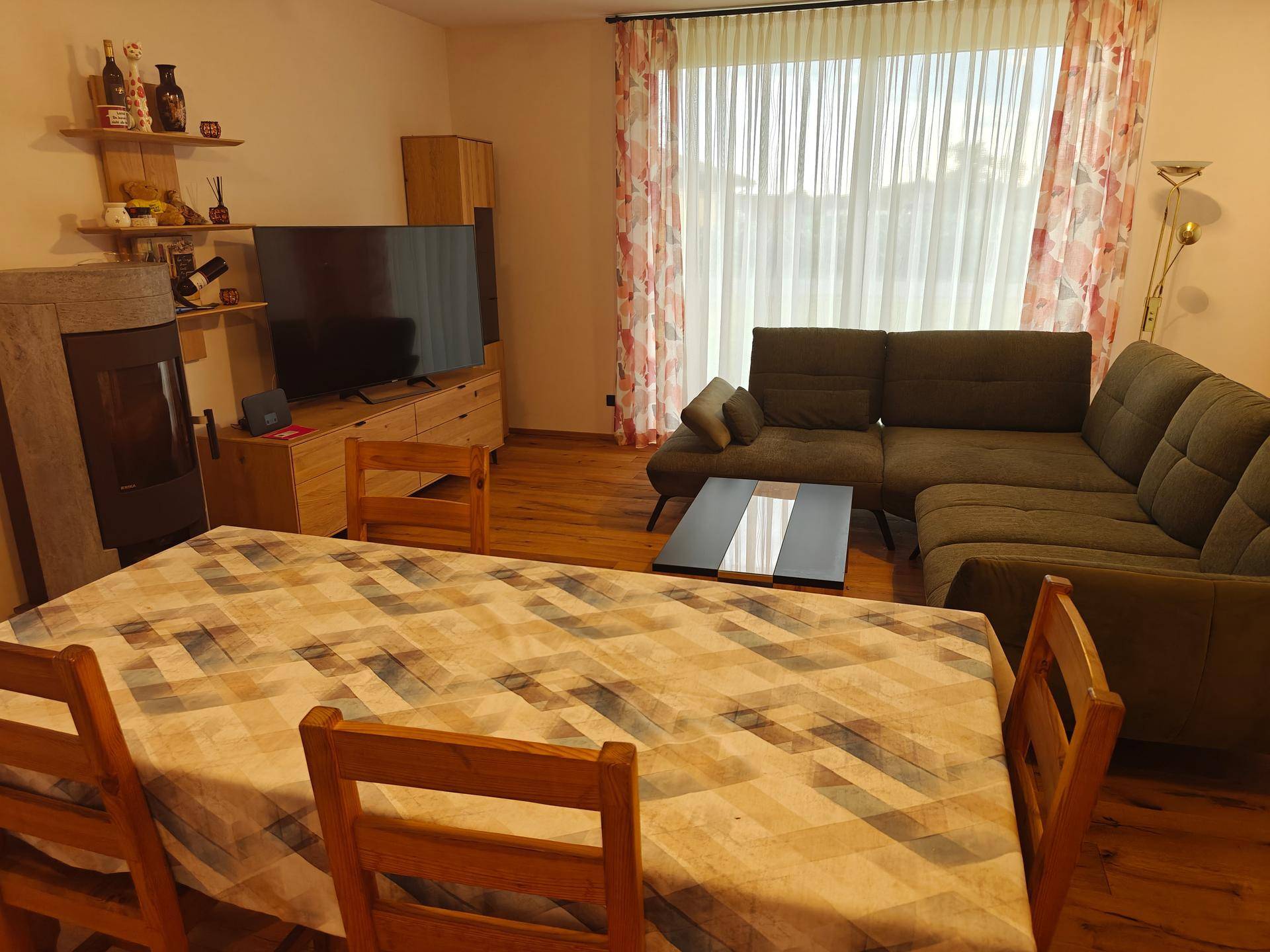 Offener Wohn-Essbereich mit Esstisch, gemütlichem Sofa und einem modernen Holzofen.