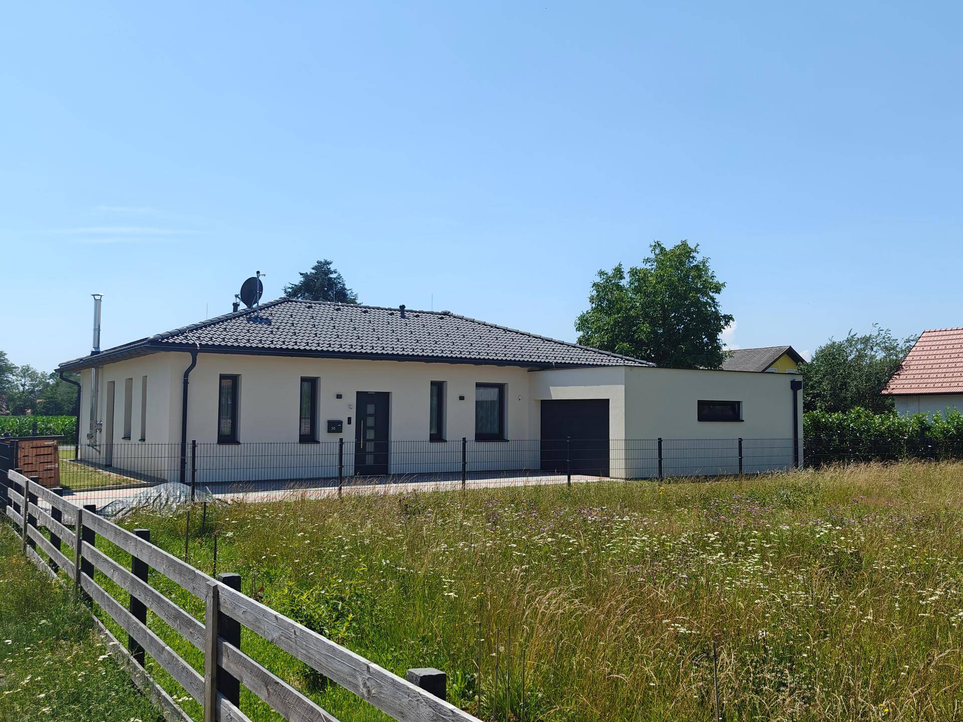 Vorderansicht eines modernen Einfamilienhauses mit Garage und großem Grundstück.