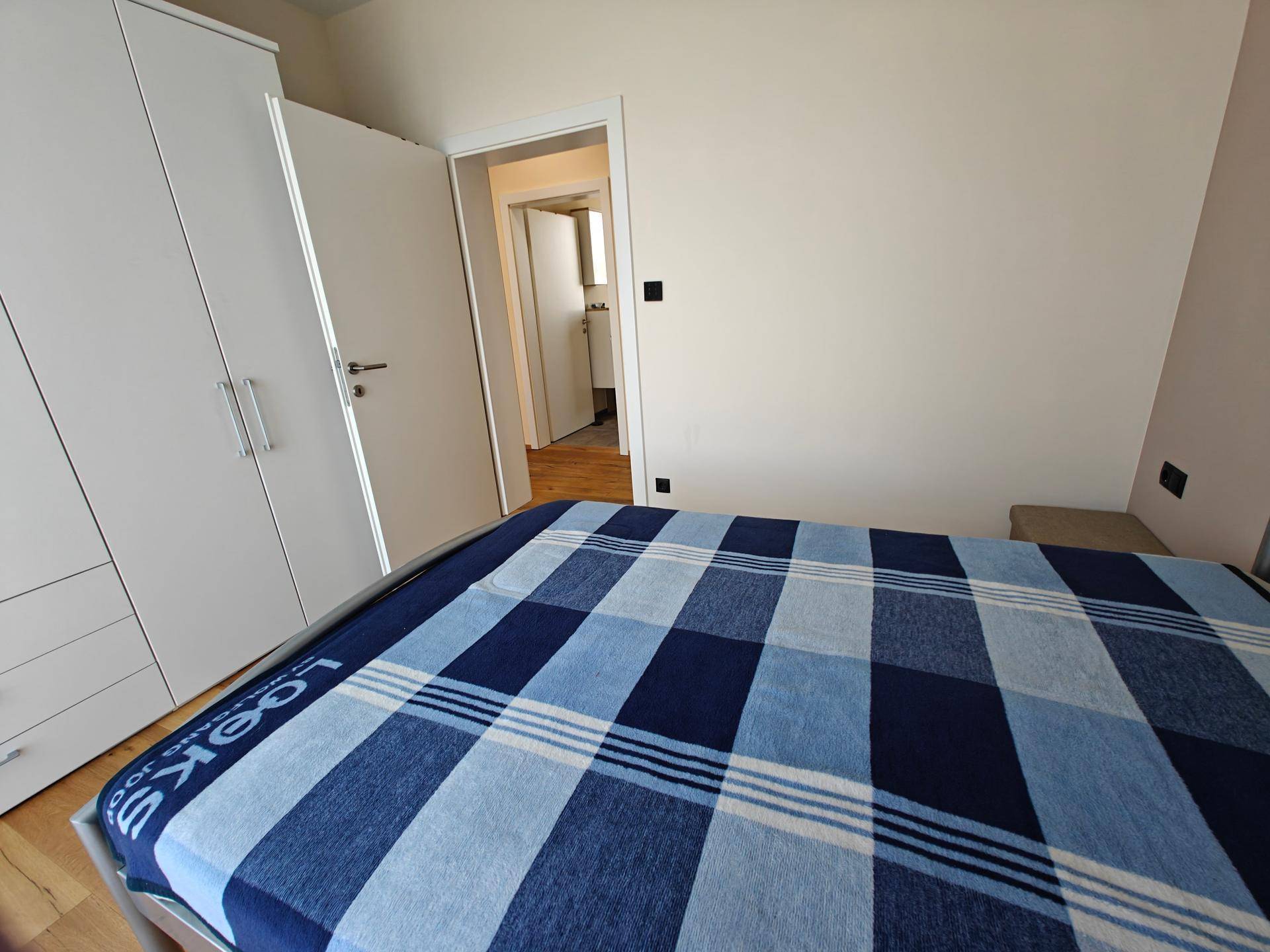 Schlafzimmer mit Einzelbett und weißem Kleiderschrank, mit Blick auf den Flur.