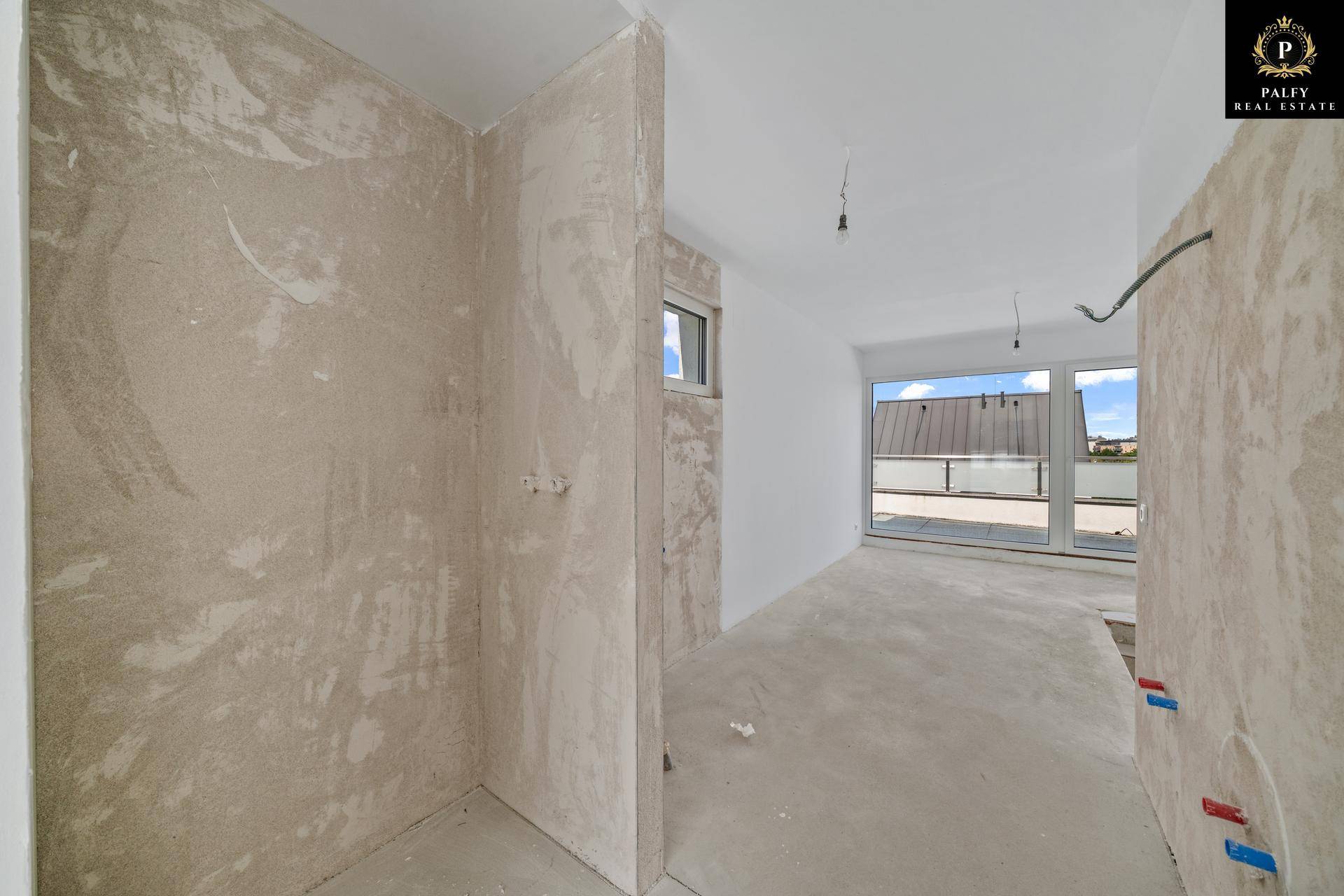 Unfertiges Badezimmer im Rohbau mit Fenster und vorbereiteten Anschlüssen für die Installation.