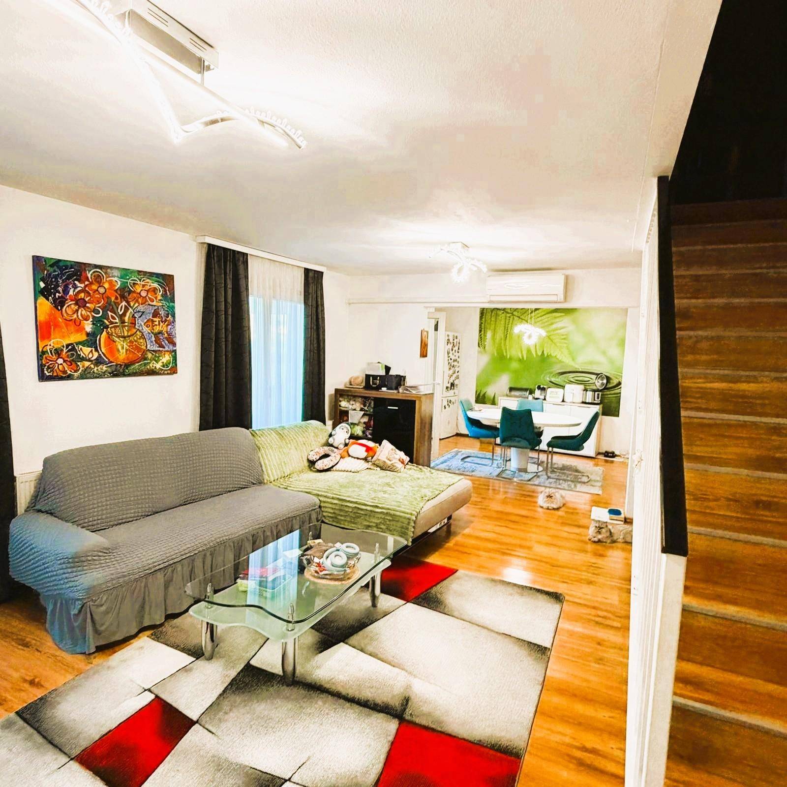 Helles Wohn- und Esszimmer mit Holzboden, bequemen Sofas und einem Essbereich im Hintergrund.