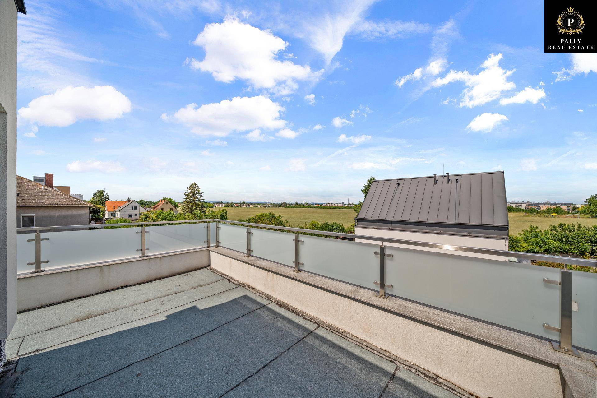 Große Dachterrasse mit Glasgeländer und weitem Blick über die grüne Landschaft.
