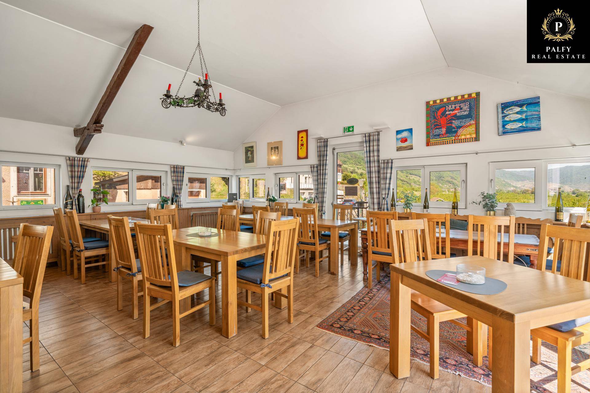 Geräumiger Speisesaal mit Holztischen und Stühlen, Fliesenboden und Blick auf die Landschaft.