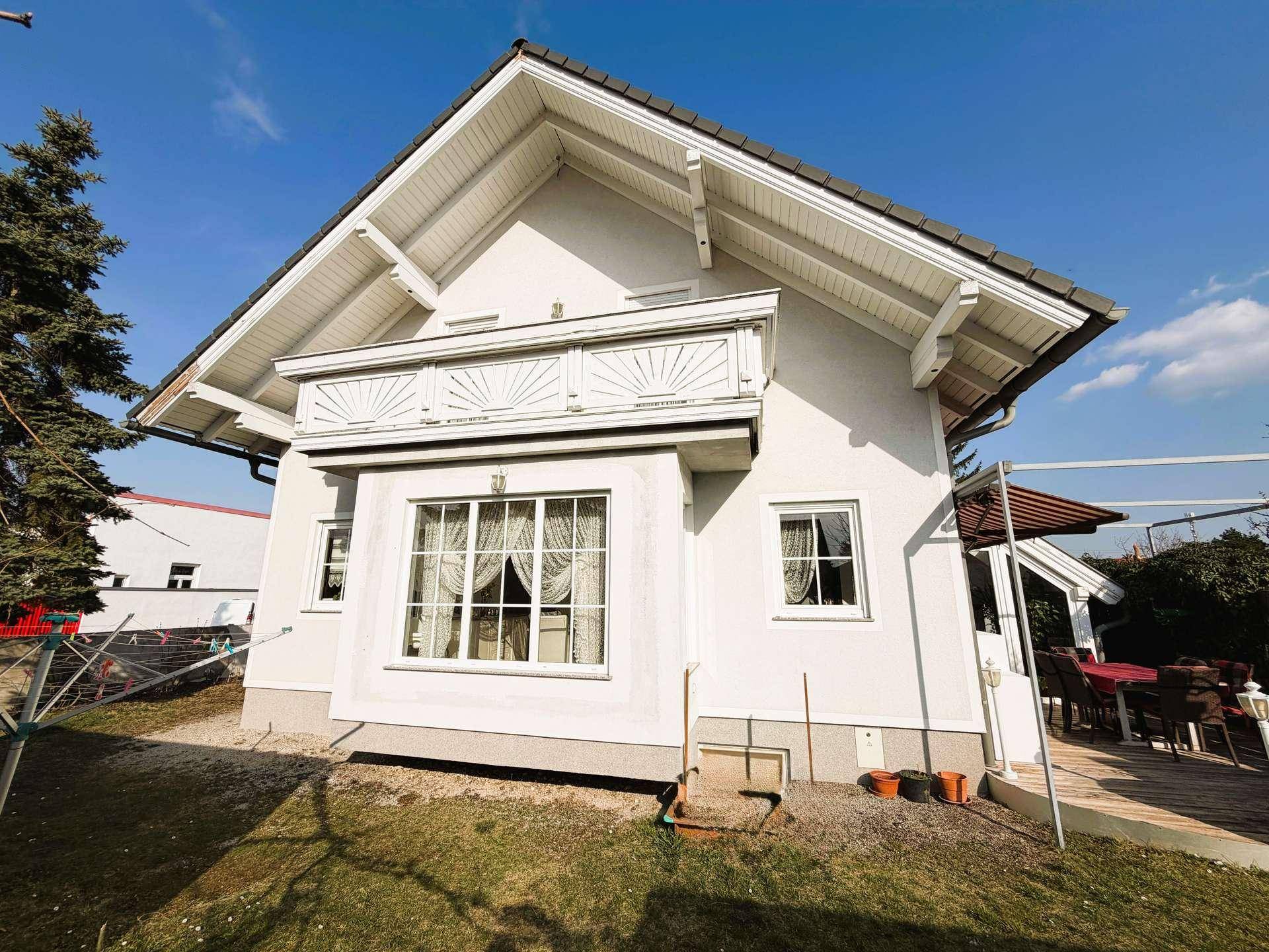 Seitenansicht des Hauses mit Erkerfenster und einem kleinen Balkon über dem Eingangsbereich.