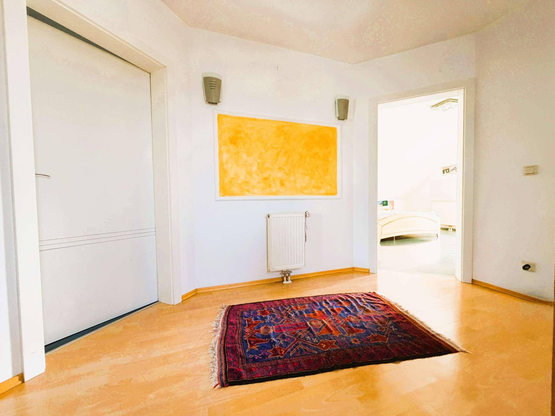 Freundlicher Flur mit Holzboden, einem Heizkörper und einem farbigen Wandbild, das zu weiteren Räumen führt.