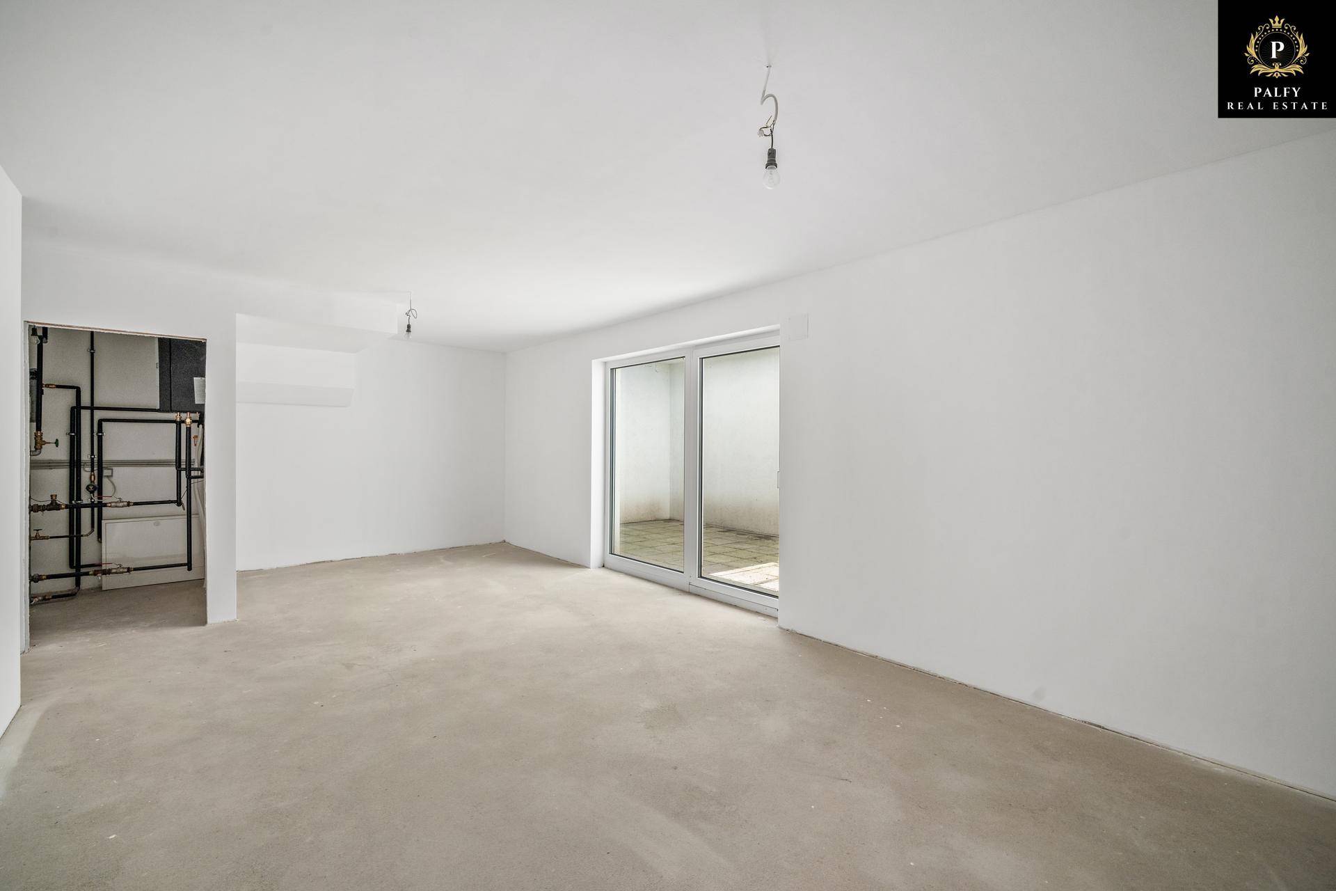 Geräumiger, unmöblierter Raum im Rohbau mit großen Fenstern und viel Tageslicht, bereit für den Ausbau.