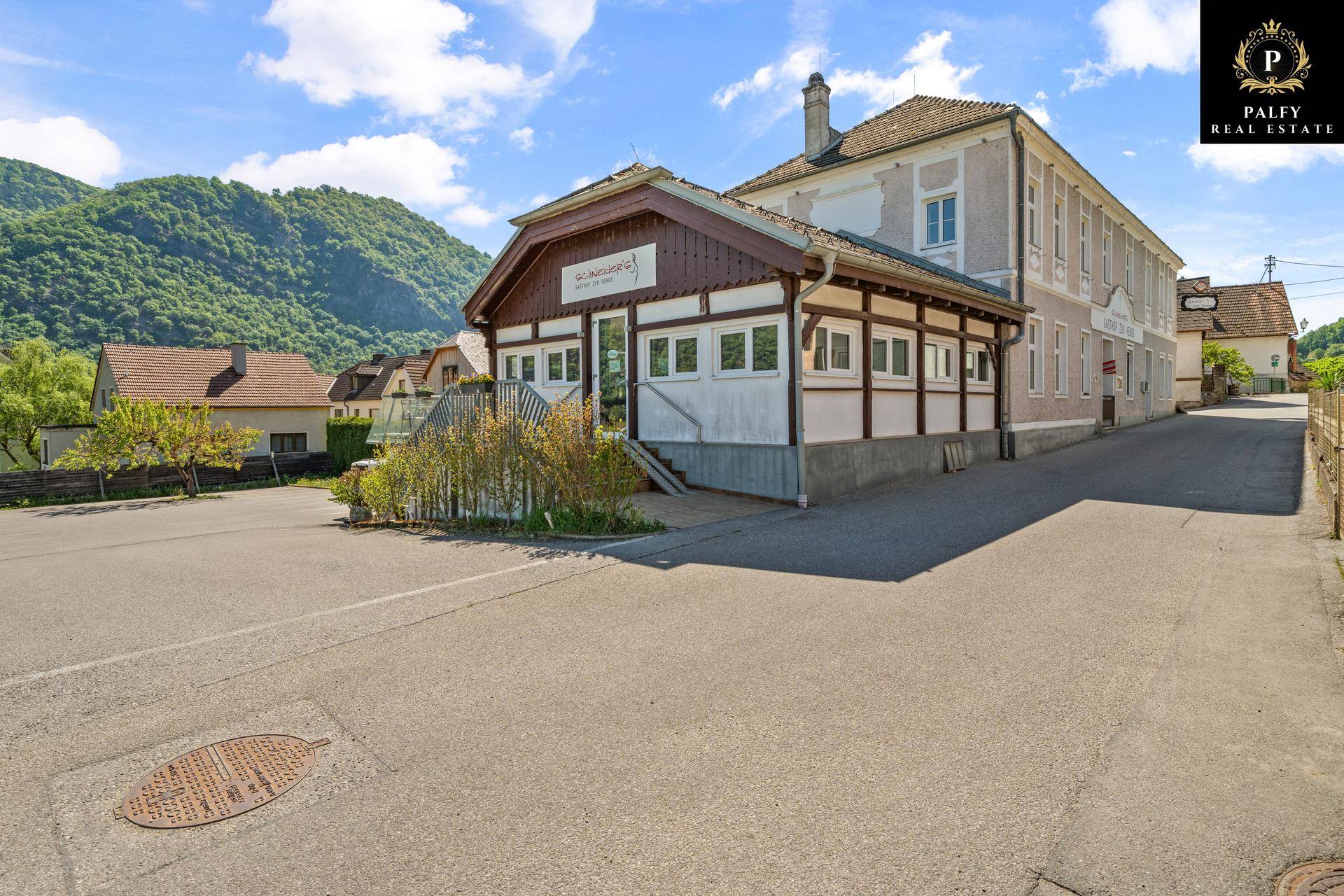 Vorderansicht eines Gasthofs mit traditioneller Holzverkleidung und einem Parkplatz davor.