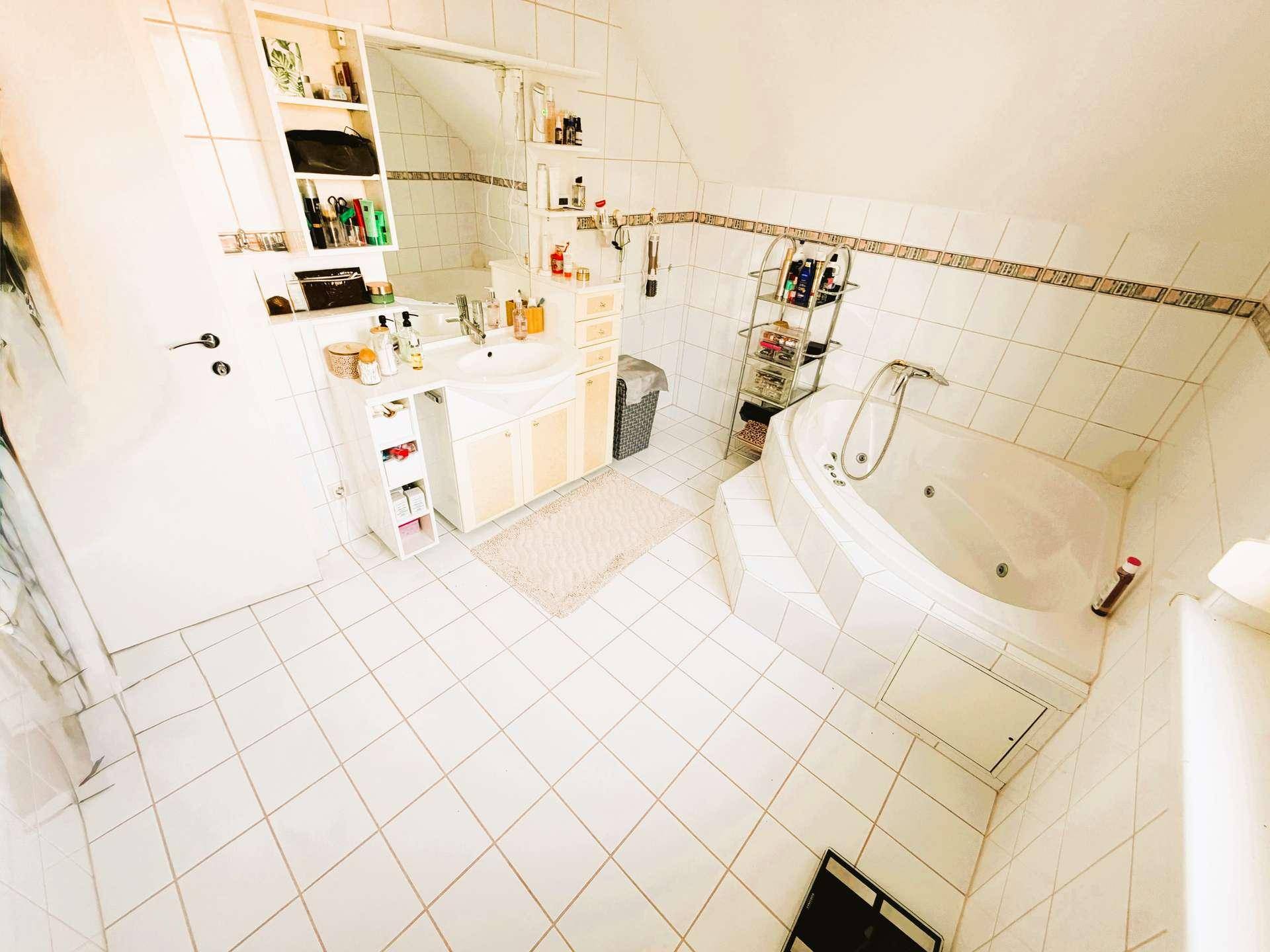 Geräumiges Badezimmer im Dachgeschoss mit Eck-Whirlpool, Einzelwaschbecken und hellen Fliesen.
