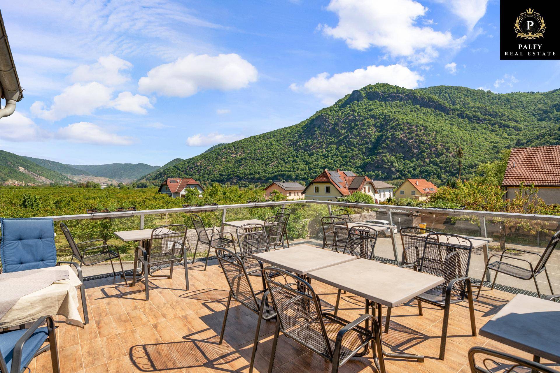 Geräumige Terrasse mit Tischen und Stühlen, ideal für Mahlzeiten im Freien mit Bergblick.