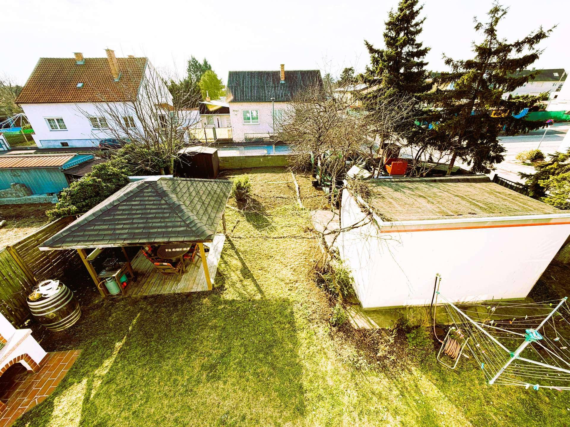 Vogelperspektive des Gartens mit Pavillon und umliegenden Wohnhäusern in sonniger Lage.