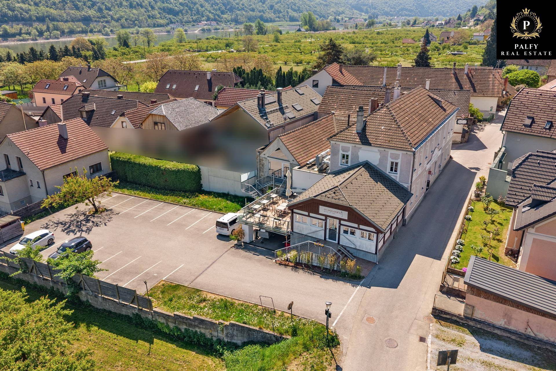 Luftaufnahme des Gasthofs mit angrenzendem Parkplatz und umliegenden Häusern.