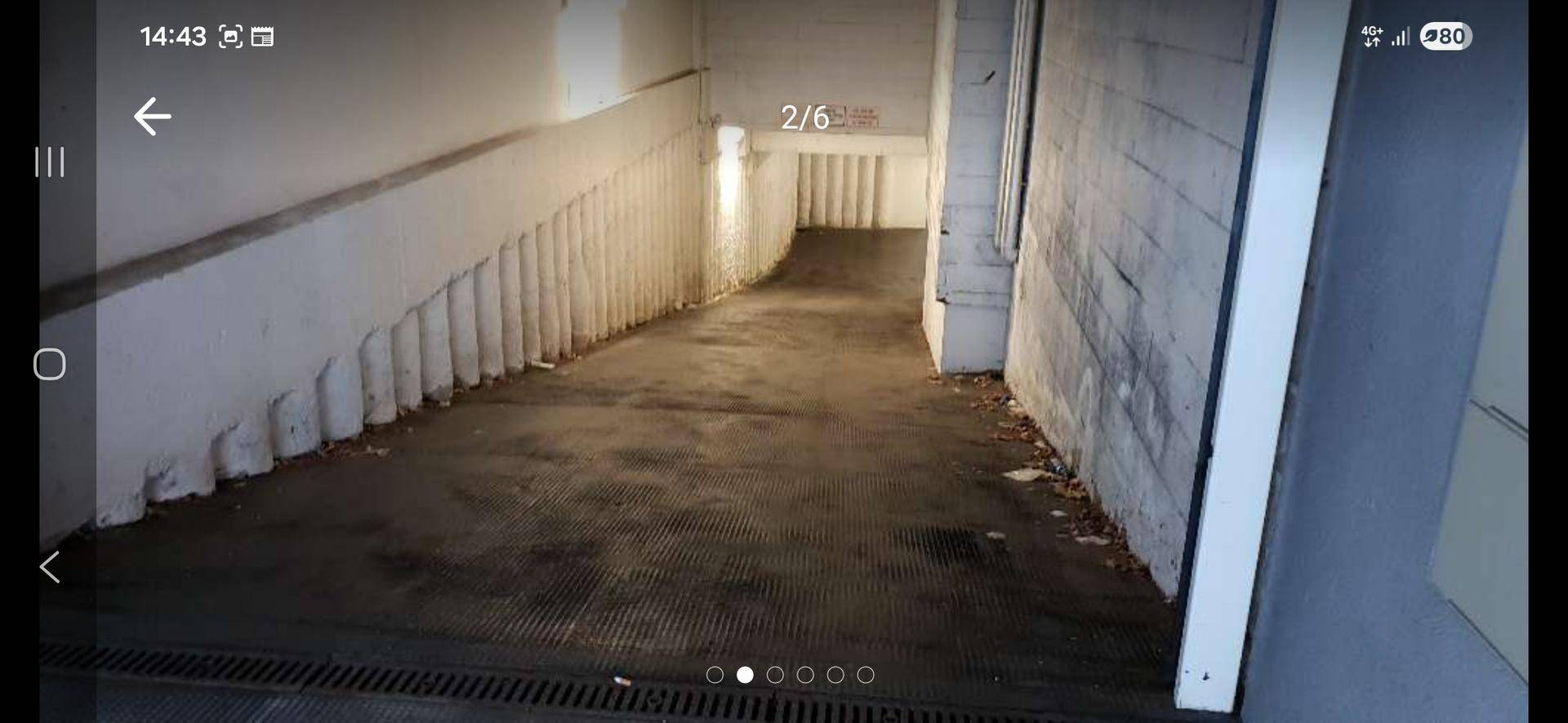 Abfahrt zu einer Tiefgarage oder einem Kellerbereich mit weiß gestrichenen Wänden und funktionaler Beleuchtung.
