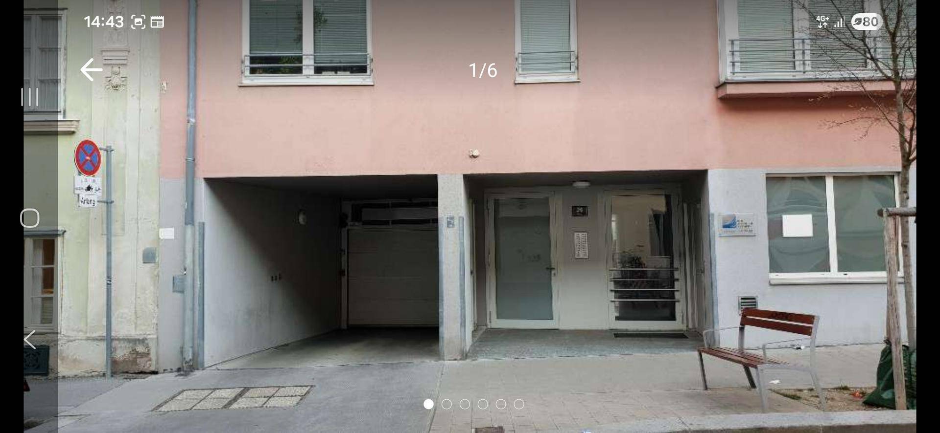 Fassade eines Wohngebäudes mit Eingangsbereich und offener Garageneinfahrt im Erdgeschoss.