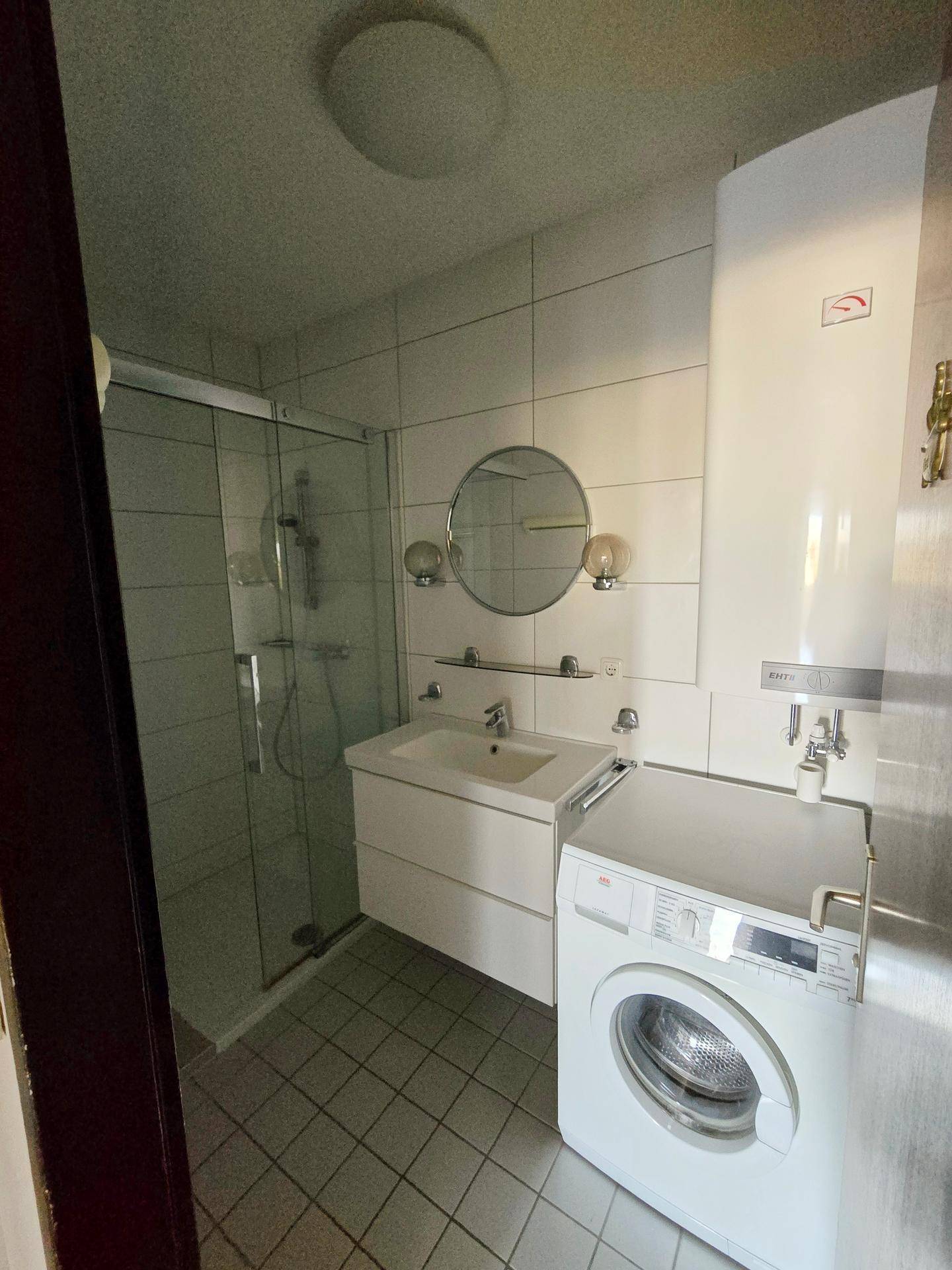 Modernes Badezimmer mit Dusche, Einzelwaschbecken und integrierter Waschmaschine.