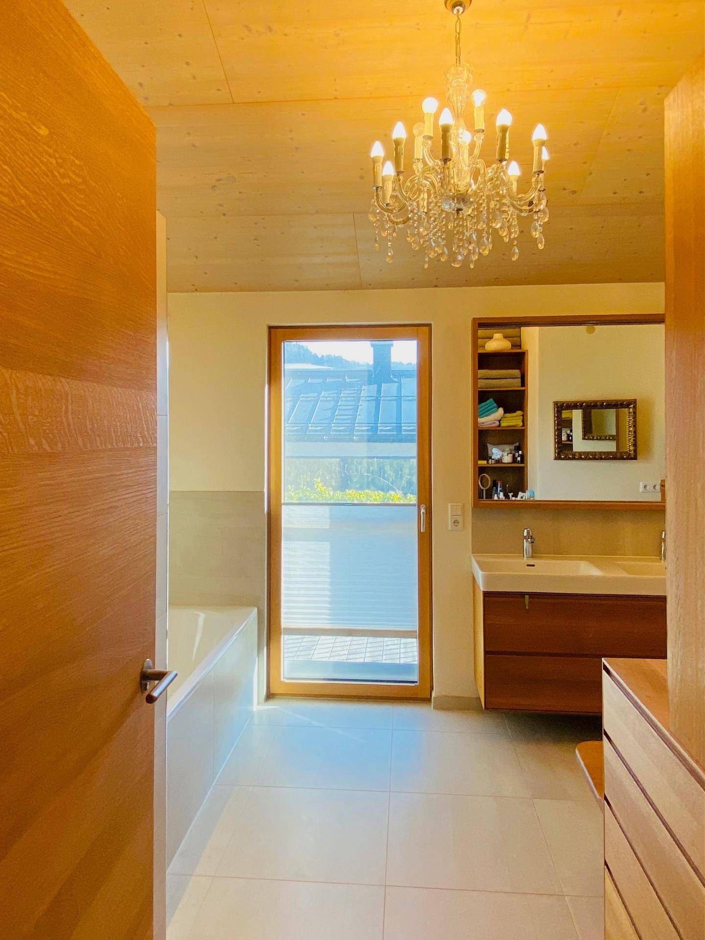 Modernes Badezimmer mit Doppelwaschbecken, Badewanne und Fenster für natürliches Licht.