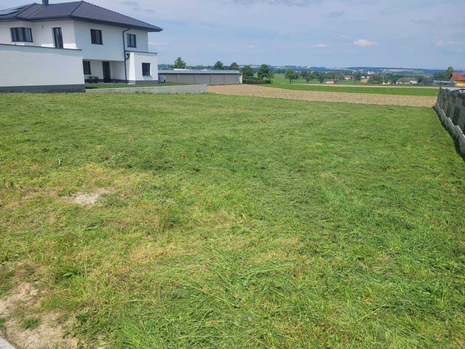 Gepflegtes Grundstück mit frisch gemähtem Rasen und Blick auf die umliegende Landschaft.
