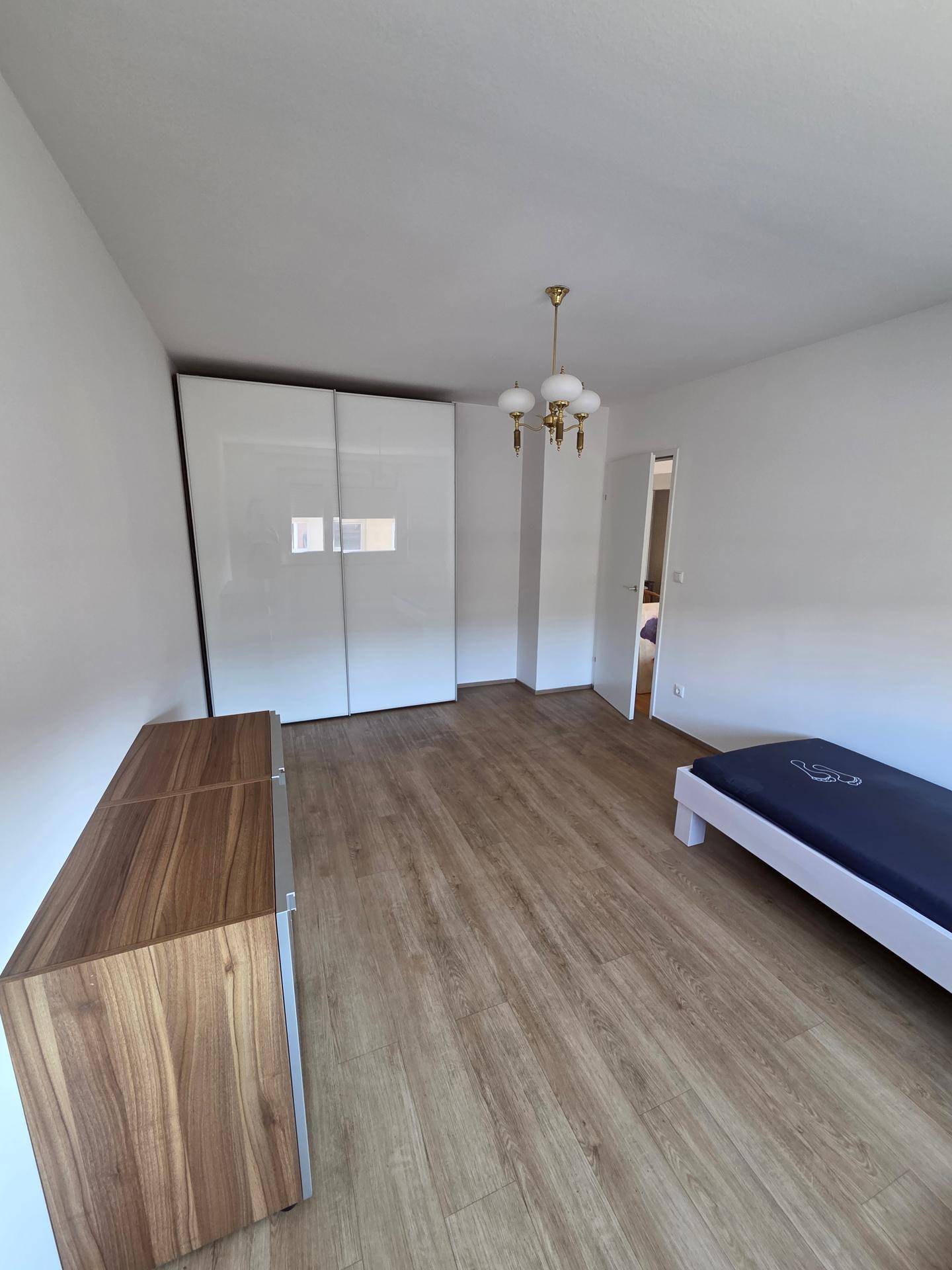 Schlafzimmer mit Holzboden, großem Kleiderschrank und Kommode.
