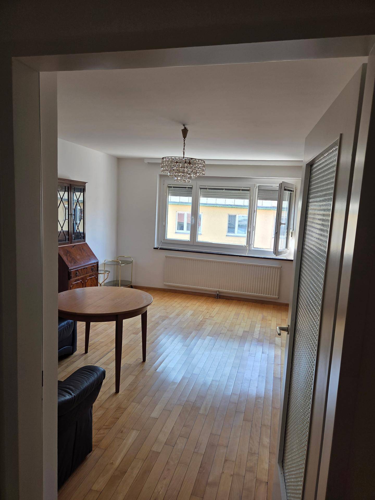 Helles Wohnzimmer mit Holzboden, Esstisch und Blick aus dem Fenster.