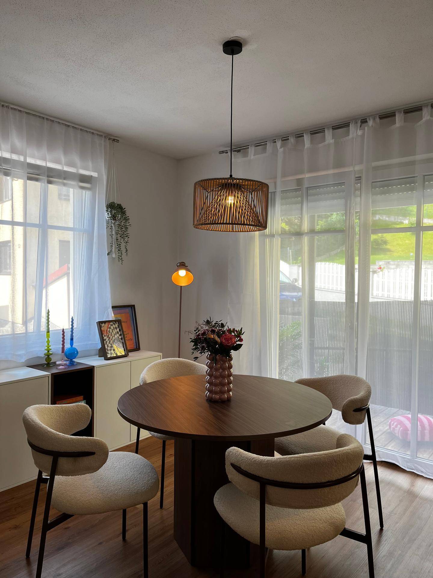 Gemütlicher Essbereich mit rundem Holztisch, modernen Stühlen und natürlichem Licht durch große Fenster.