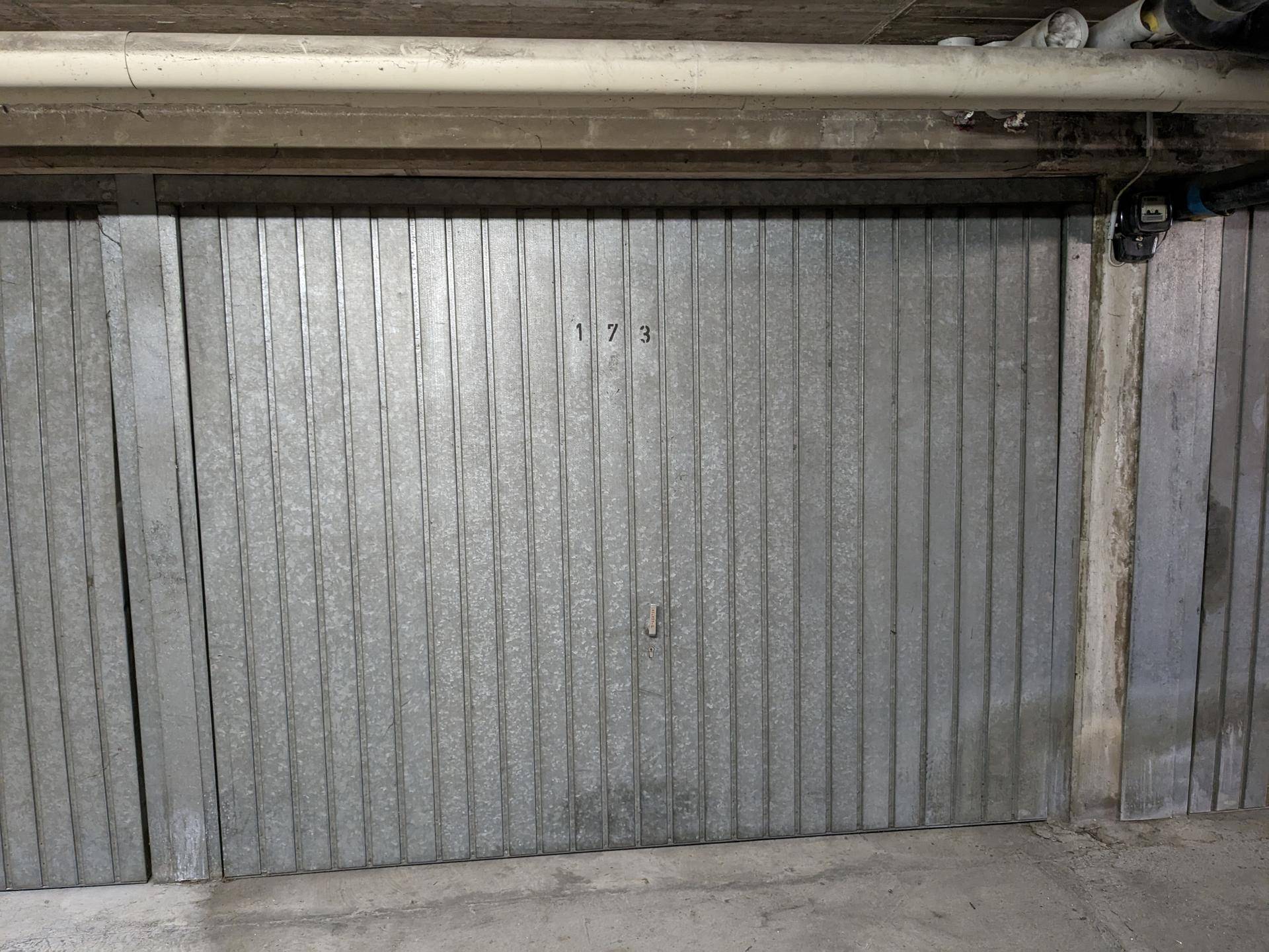 Einzelne Garagenbox mit Metalltor und Nummerierung in der Tiefgarage.