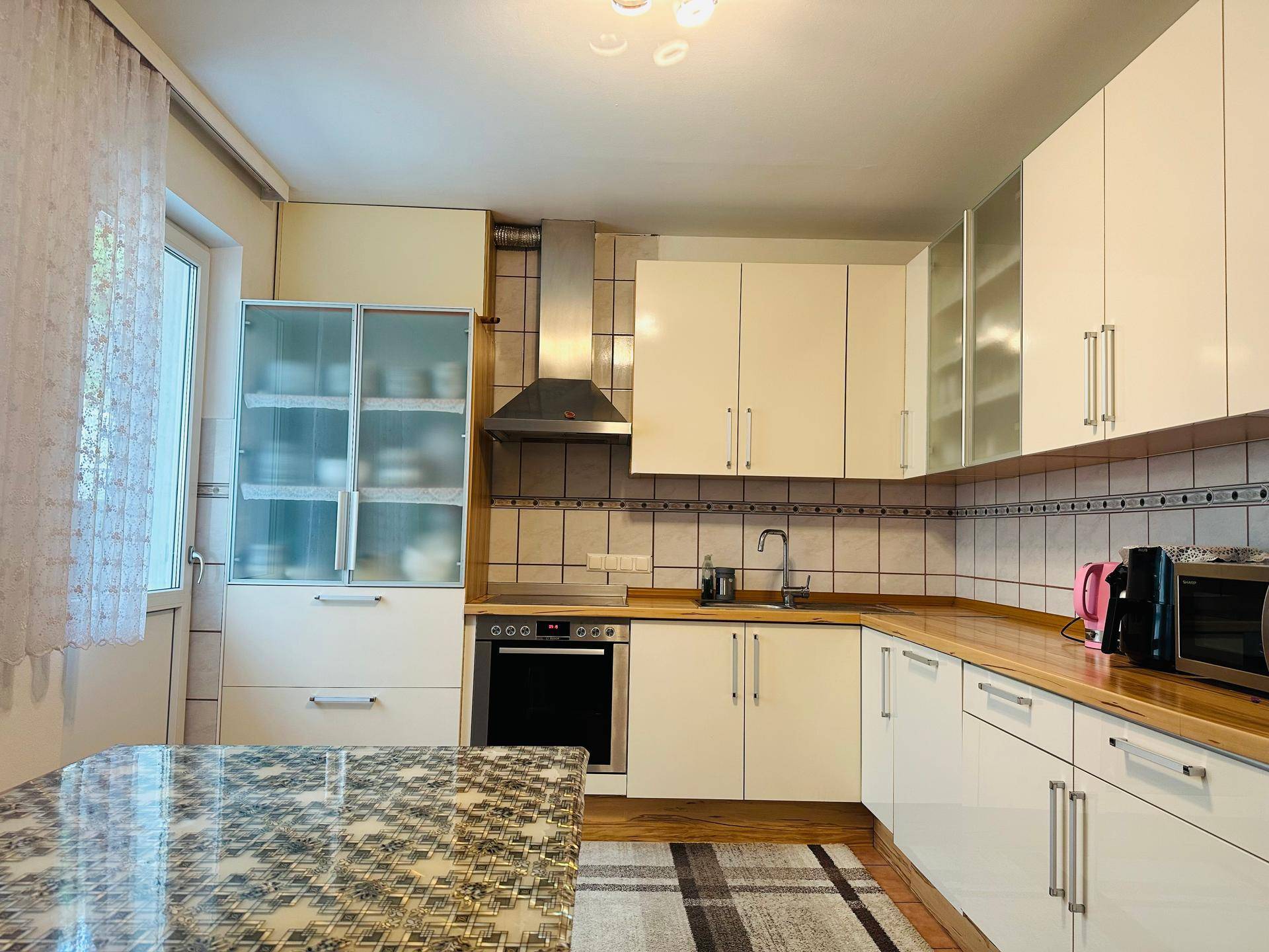 Funktionale Küche mit weißen Schränken, Holz-Arbeitsplatten und integrierten Geräten.