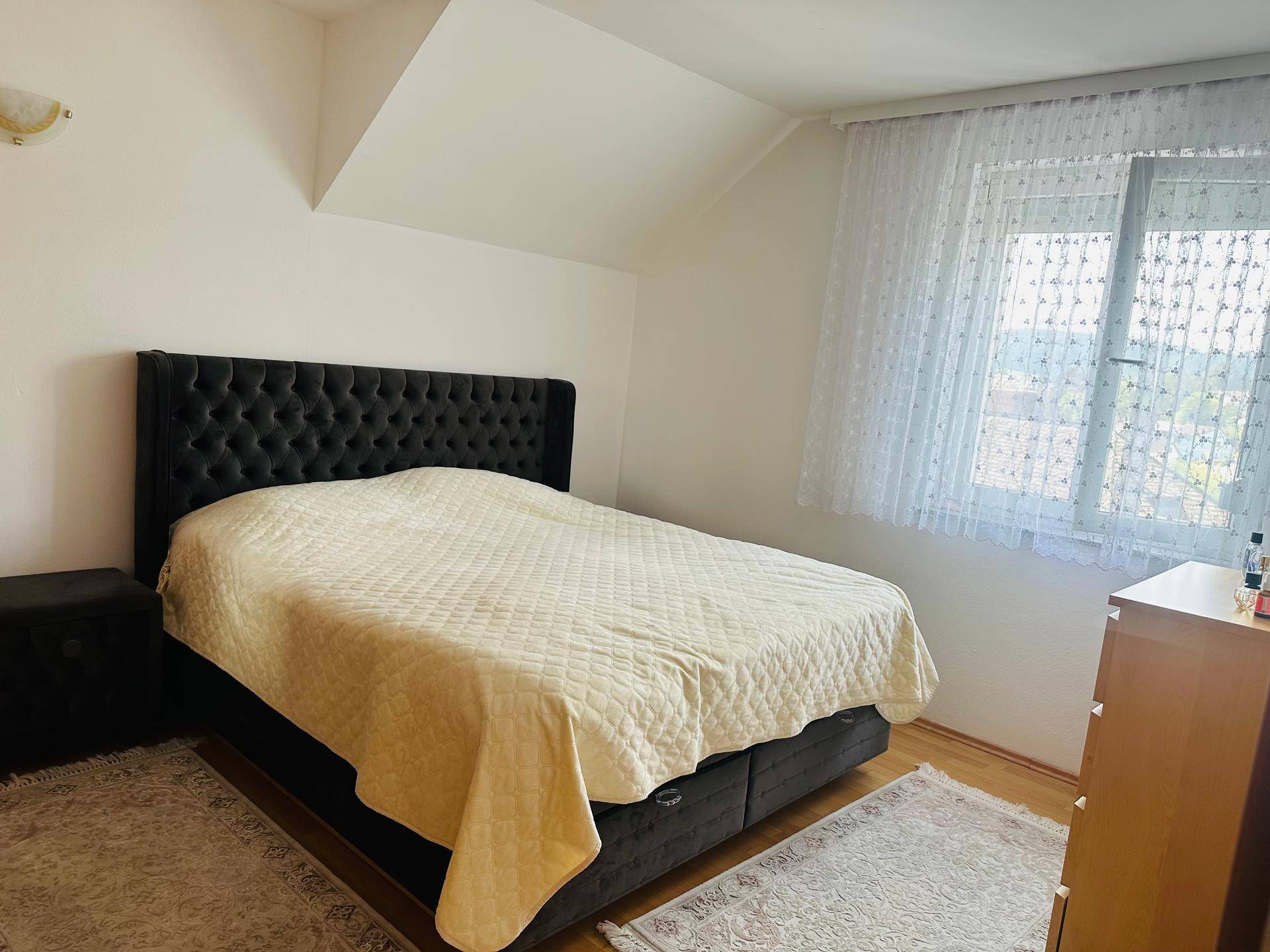 Geräumiges Schlafzimmer mit großem Doppelbett, Nachttisch und Dachschräge.