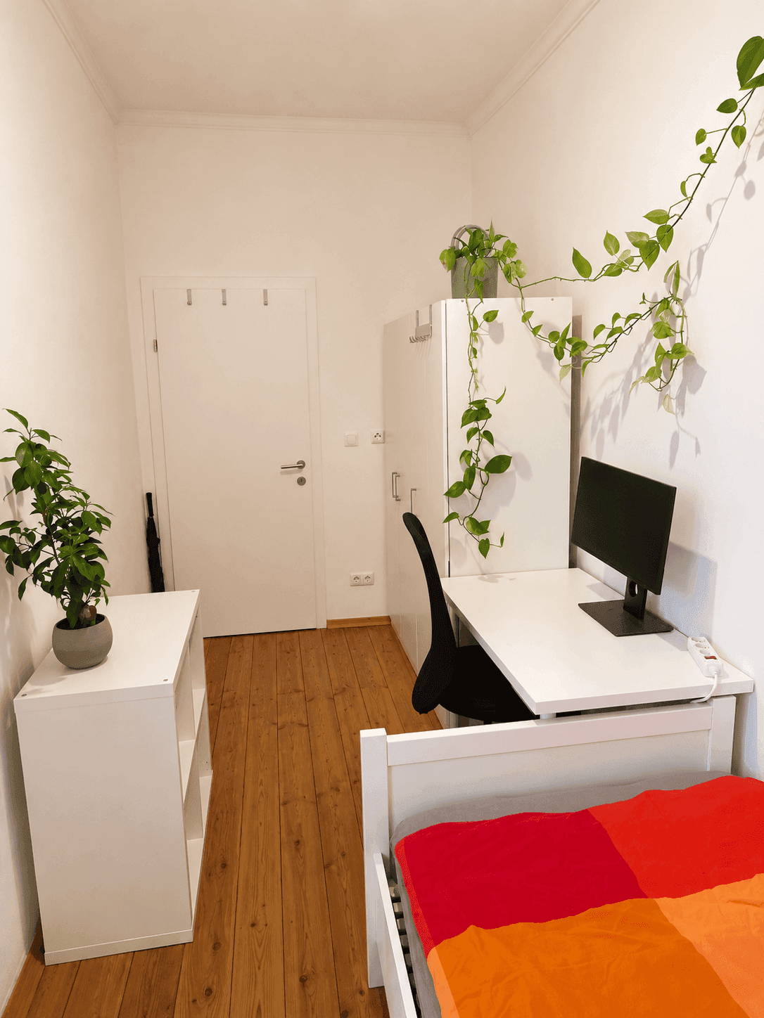 Gemütliches Schlafzimmer mit Holzboden, Kleiderschrank und Schreibtisch, ideal für Studenten.