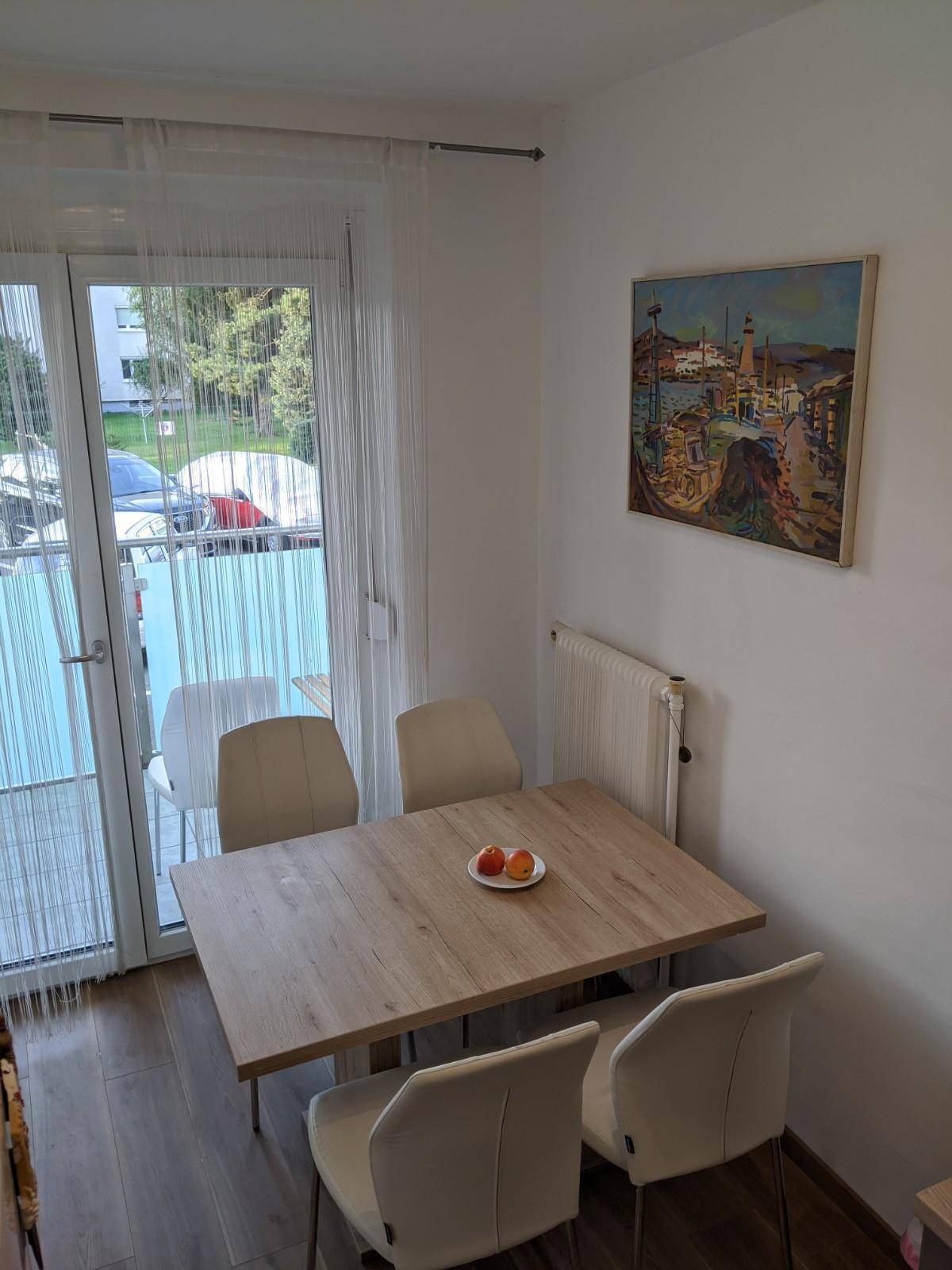 Heller Essbereich mit Holztisch und Balkonzugang, ideal für sonnige Tage.
