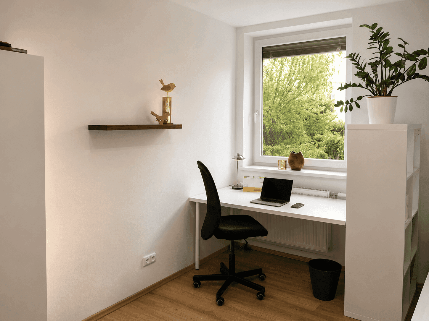 Heller Arbeitsbereich im Schlafzimmer mit Schreibtisch am Fenster und Blick ins Grüne.