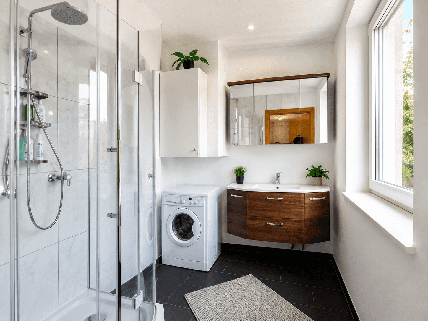 Modernes Badezimmer mit Dusche, Waschmaschine und elegantem Holzwaschtischunterschrank.