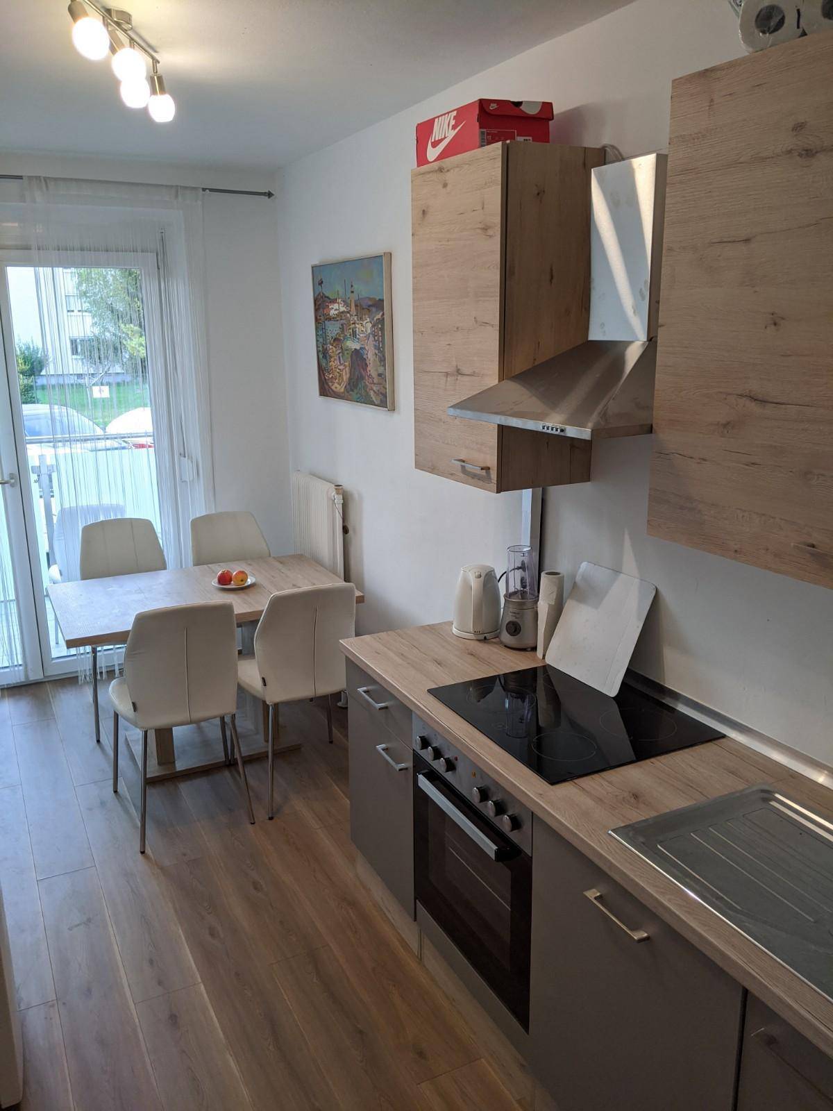 Moderne Einbauküche mit Essbereich, Holzarbeitsplatte und Zugang zum Balkon.
