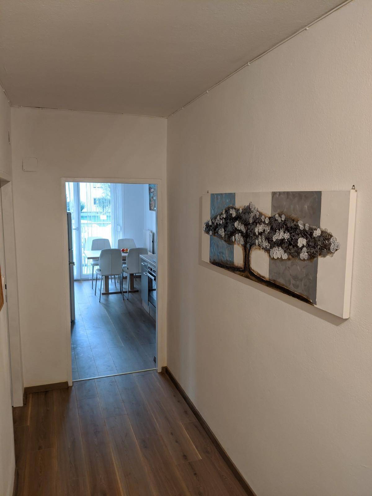 Heller Flur mit Holzboden und dekorativem Wandbild, führt zum Essbereich.
