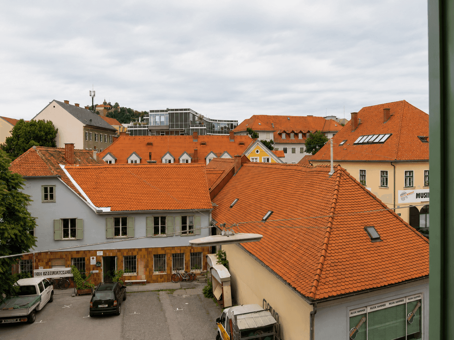 Panoramablick über die Stadt mit historischen Dächern und einem modernen Gebäudeensemble.