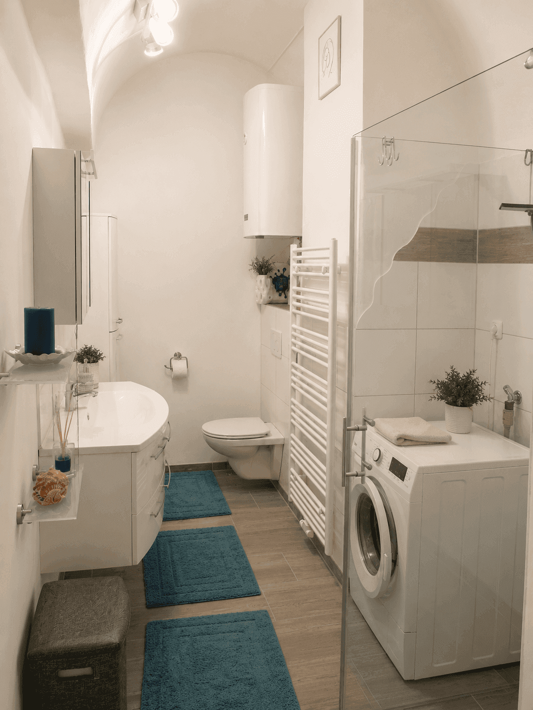 Modernes Badezimmer mit Dusche, Waschbecken, WC, Waschmaschine und beheiztem Handtuchhalter.