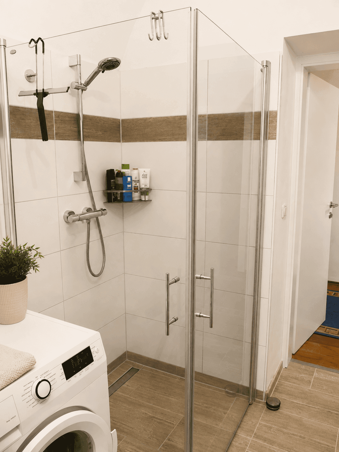 Duschbereich im modernen Badezimmer mit Glasabtrennung und Fliesenboden in Holzoptik.