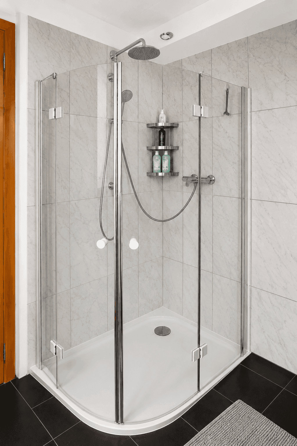 Eckdusche mit Glasabtrennung und Regenduschkopf in einem modern gefliesten Badezimmer.