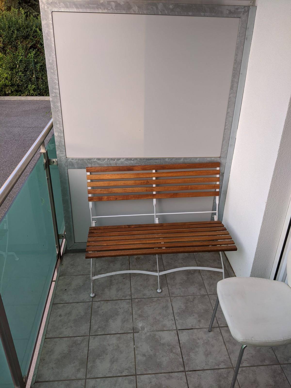 Gemütlicher Balkon mit Holzbank und Fliesenboden, ideal zum Entspannen.