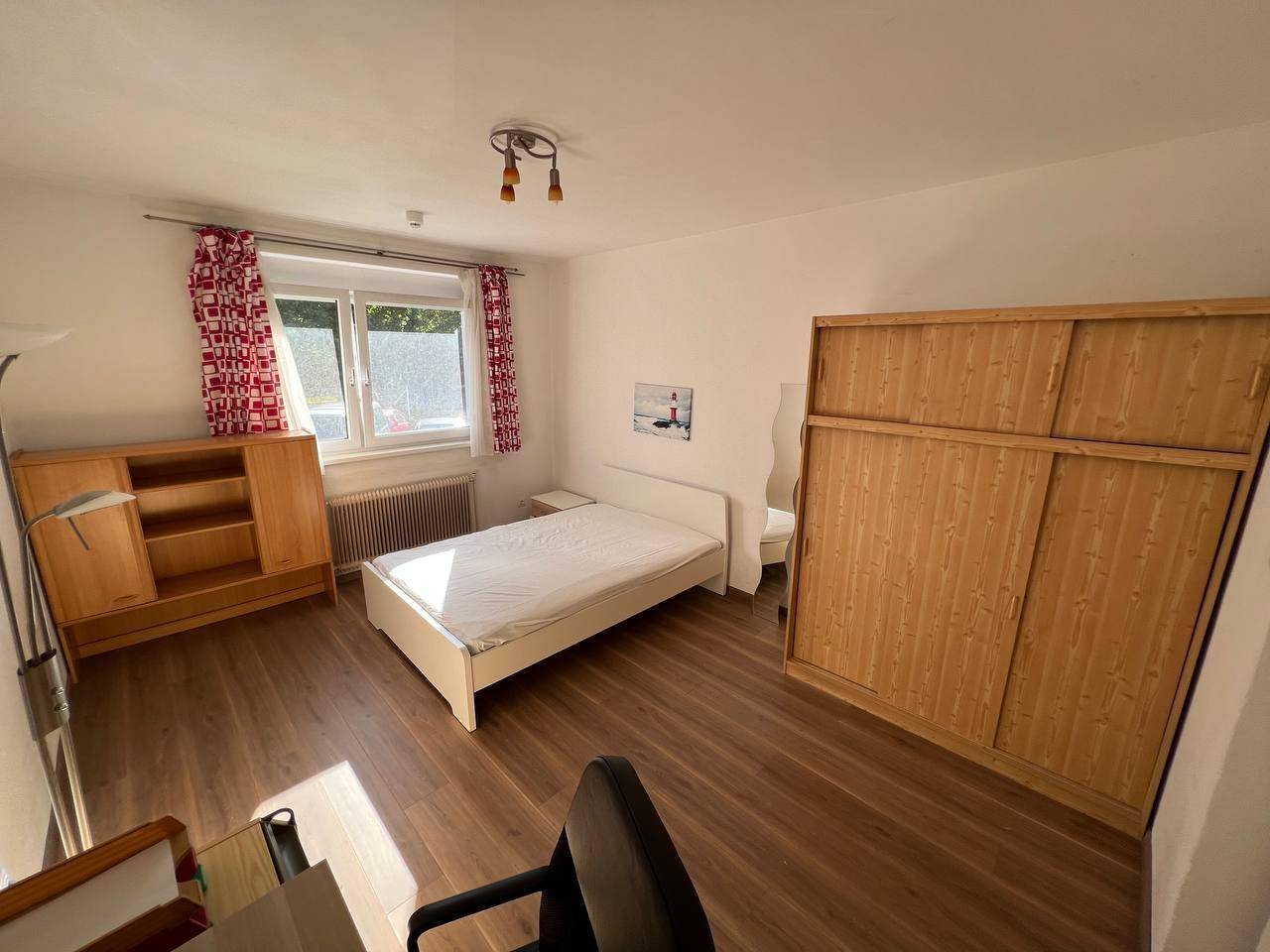 Geräumiges Schlafzimmer mit großem Kleiderschrank, Einzelbett und Holzboden.