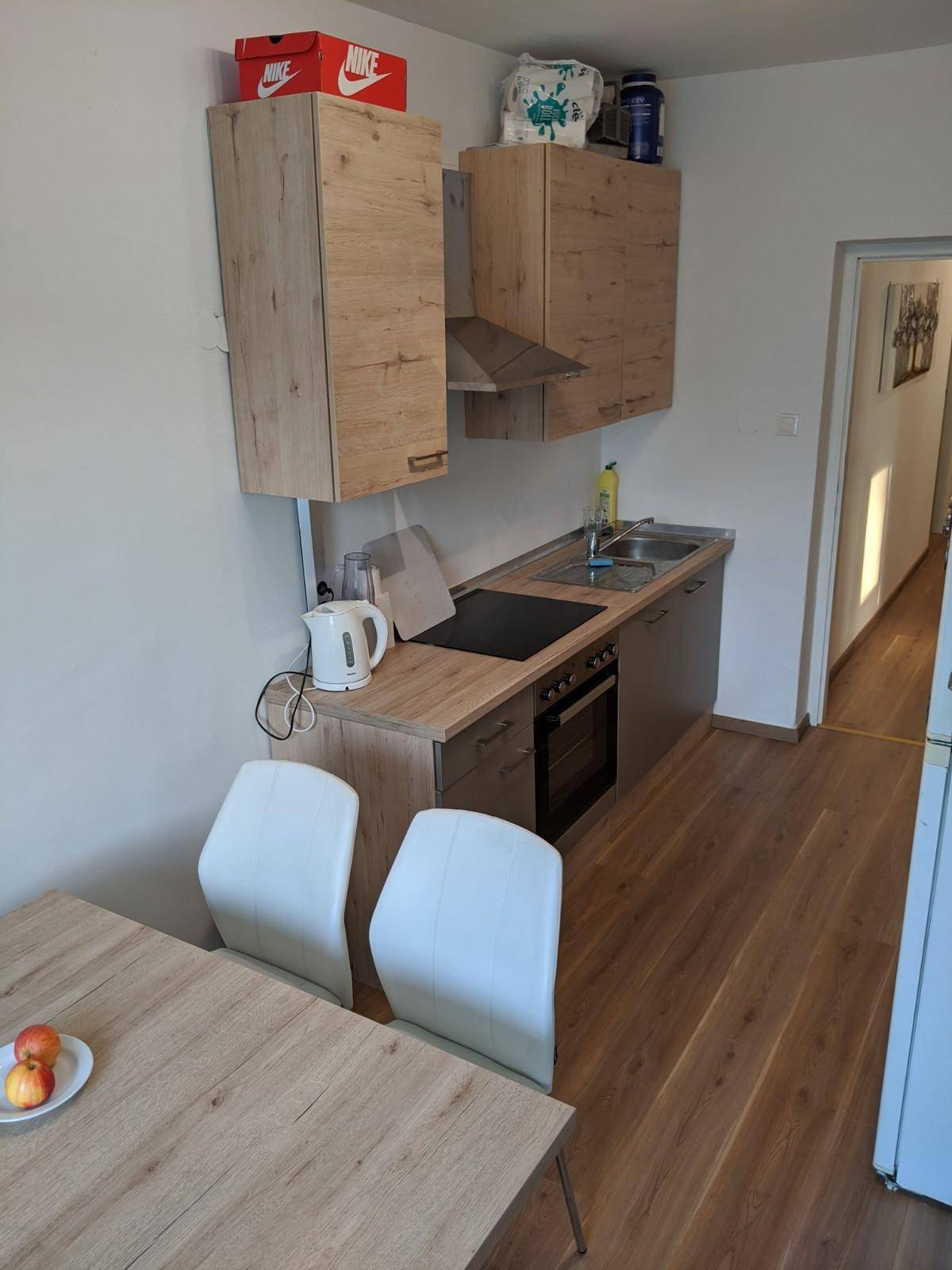 Funktionale Küche mit Essbereich, Holzschränken und Blick in den Flur.