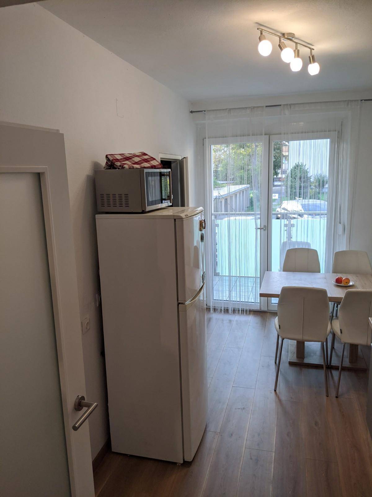 Küchenbereich mit Kühlschrank, Mikrowelle und Zugang zum hellen Balkon.