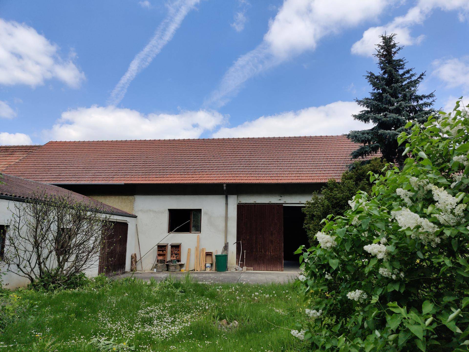 Außenansicht eines Gebäudes mit rotem Ziegeldach und einer grünen Wiese im Vordergrund.