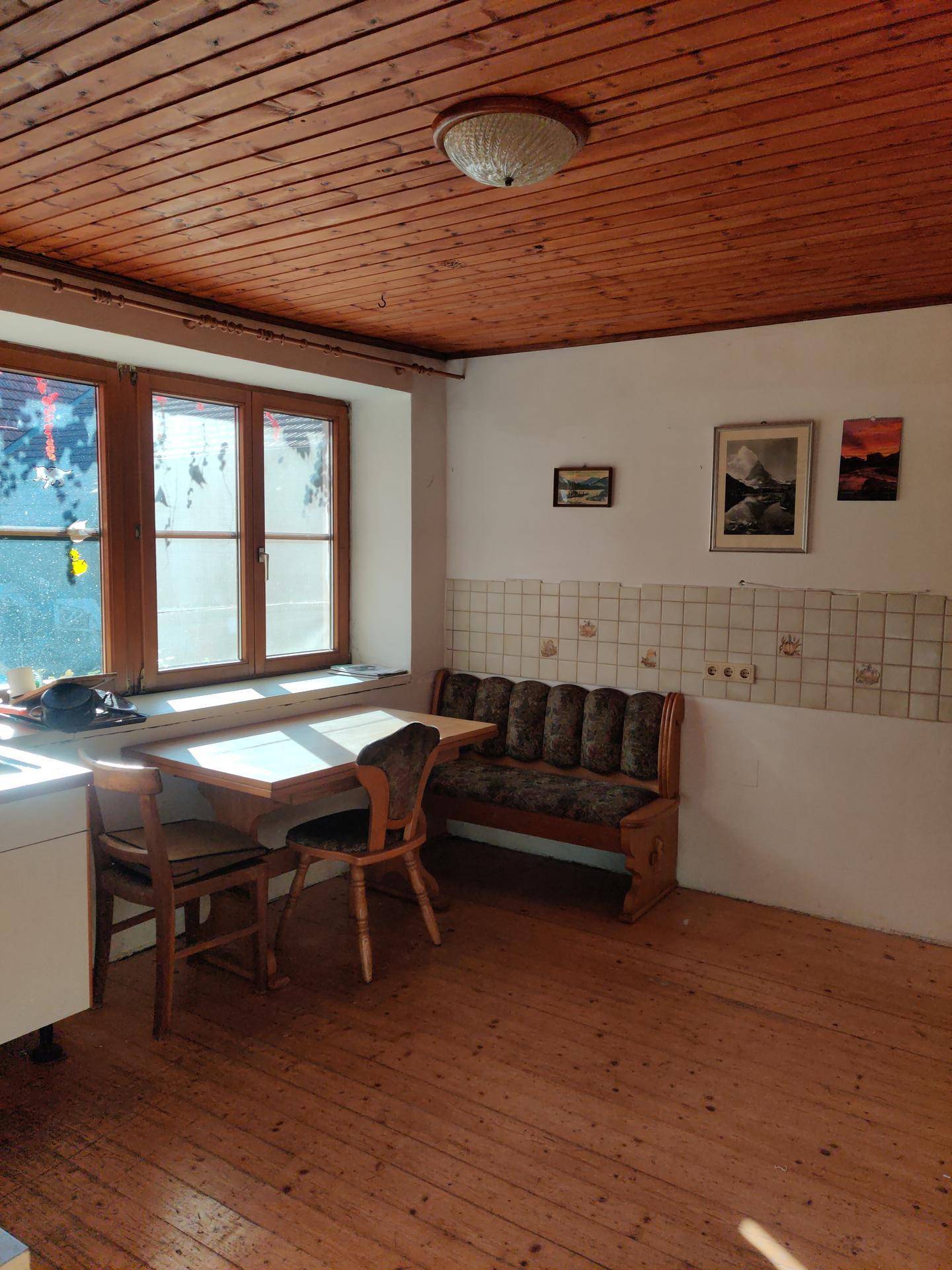 Gemütliche Küche mit Holzdielenboden, Holztäfelung an der Decke und einem Essbereich.