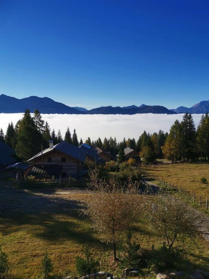 Idyllische Berglandschaft mit traditionellen Holzhäusern unter einem klaren blauen Himmel.
