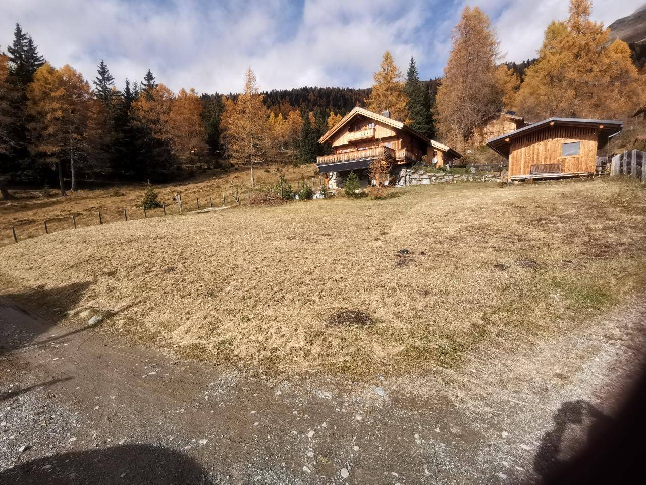 Weitläufiges Grundstück mit Chalet und Nebengebäude, eingebettet in die alpine Landschaft.