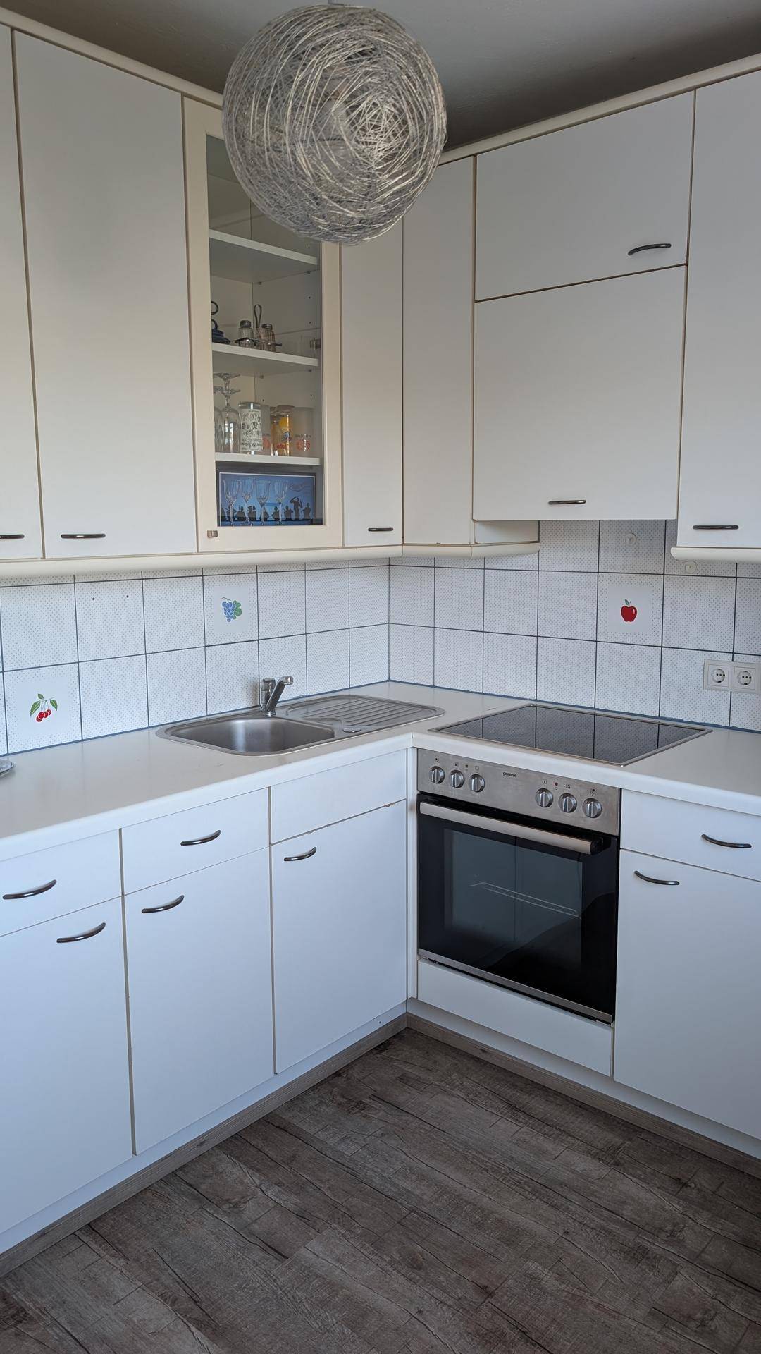 Helle Einbauküche mit weißen Schränken, Induktionskochfeld und Backofen.