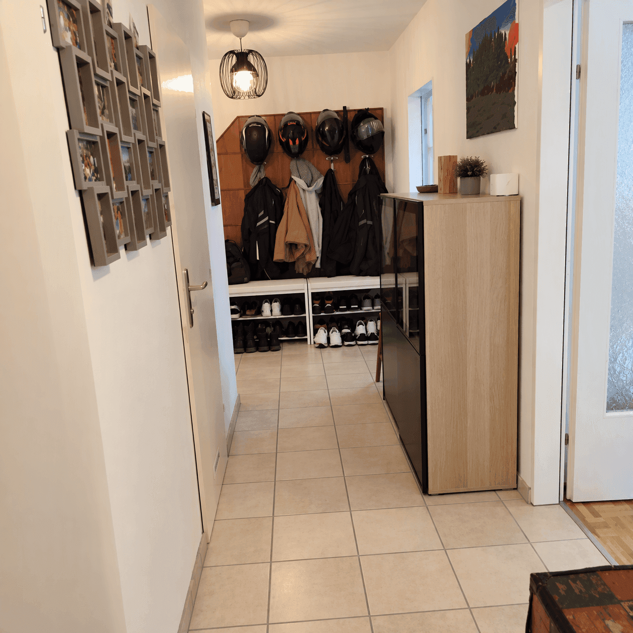 Eingangsbereich mit praktischer Garderobe, Schuhregal und hellem Fliesenboden.